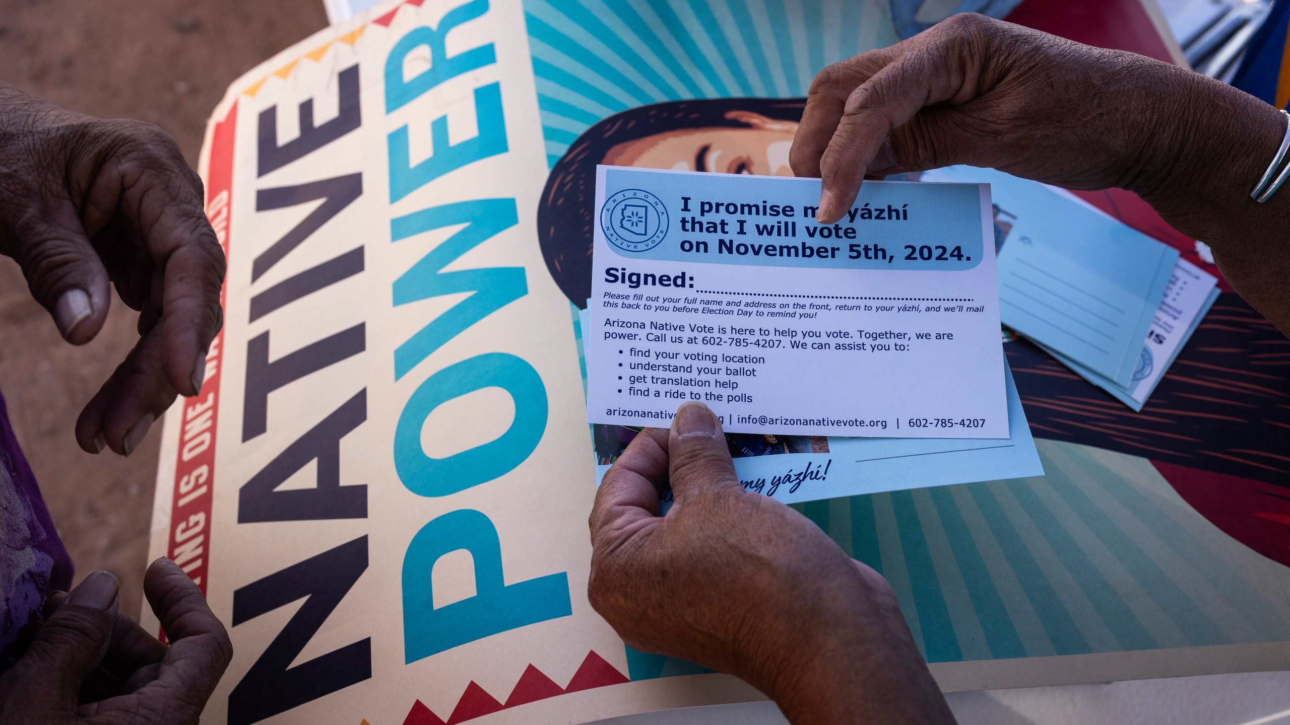 FILE - Local organizer Maria Calamity instructs a resident on how to properly fill out a pledge card promising to vote in the upcoming presidential election on the Navajo Nation in Ganado, Ariz., Oct. 11, 2024. (AP Photo/Rodrigo Abd, File)