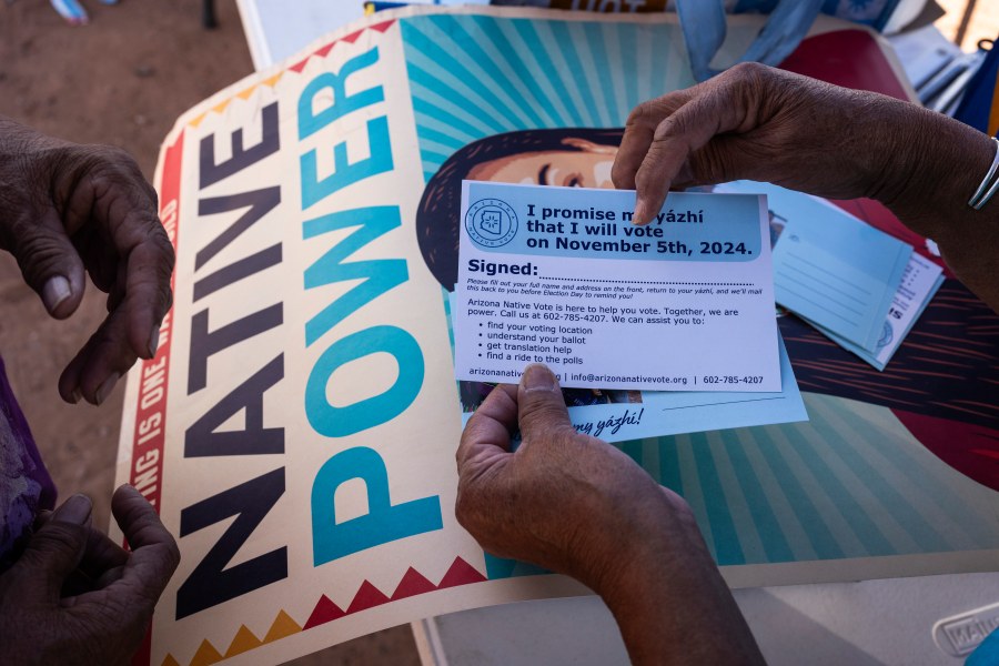 FILE - Local organizer Maria Calamity instructs a resident on how to properly fill out a pledge card promising to vote in the upcoming presidential election on the Navajo Nation in Ganado, Ariz., Oct. 11, 2024. (AP Photo/Rodrigo Abd, File)