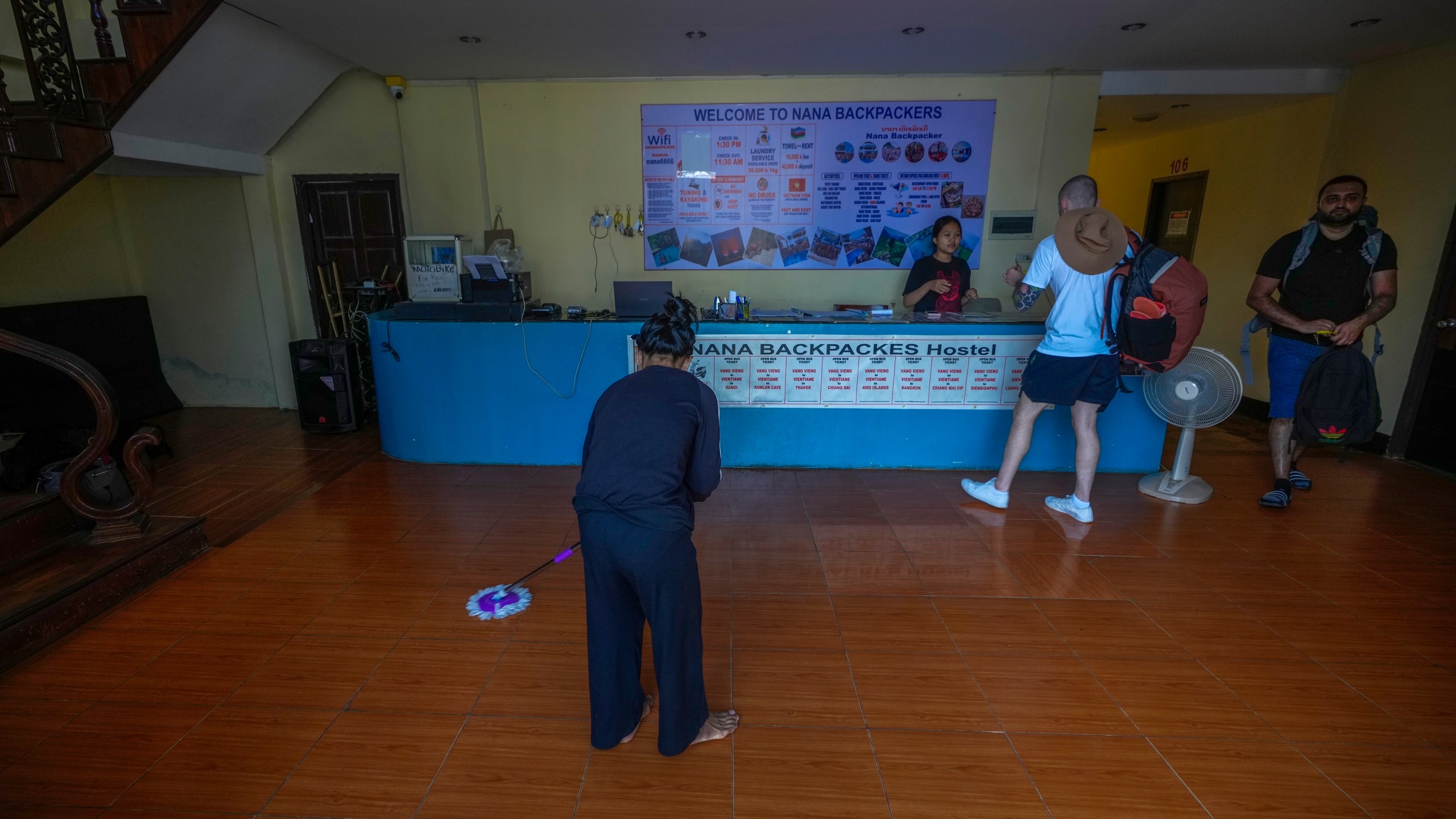 A woman swipes the floor as foreign tourists check out of Nana Backpack hostel in Vang Vieng, Laos, Tuesday, Nov. 19, 2024. (AP Photo/Anupam Nath)