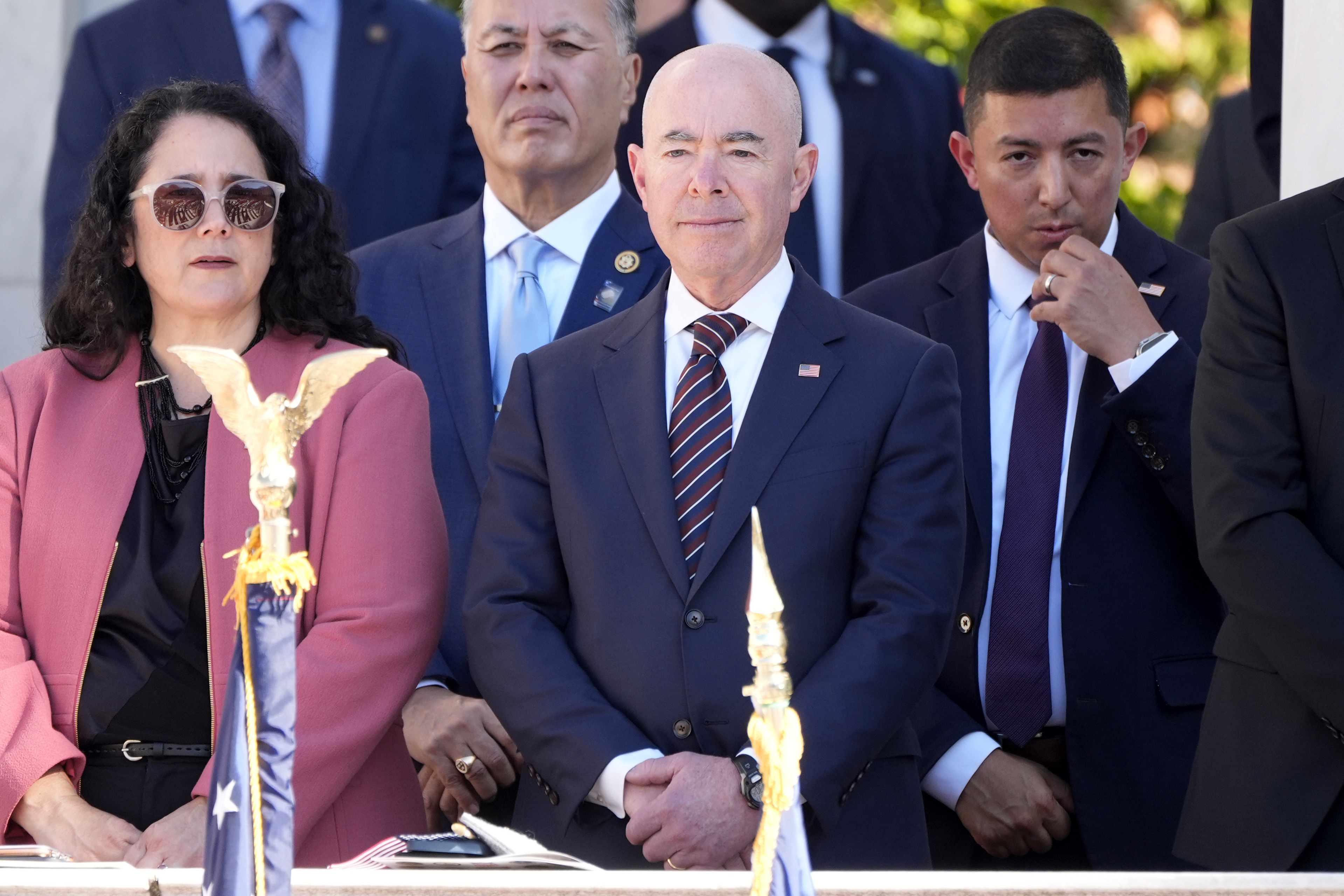 Homeland Security Secretary Alejandro Mayorkas, center, looks on before President Joe Biden speaks at the National Veterans Day Observance at the Memorial Amphitheater at Arlington National Cemetery in Arlington, Va., Monday, Nov. 11, 2024. (AP Photo/Mark Schiefelbein)