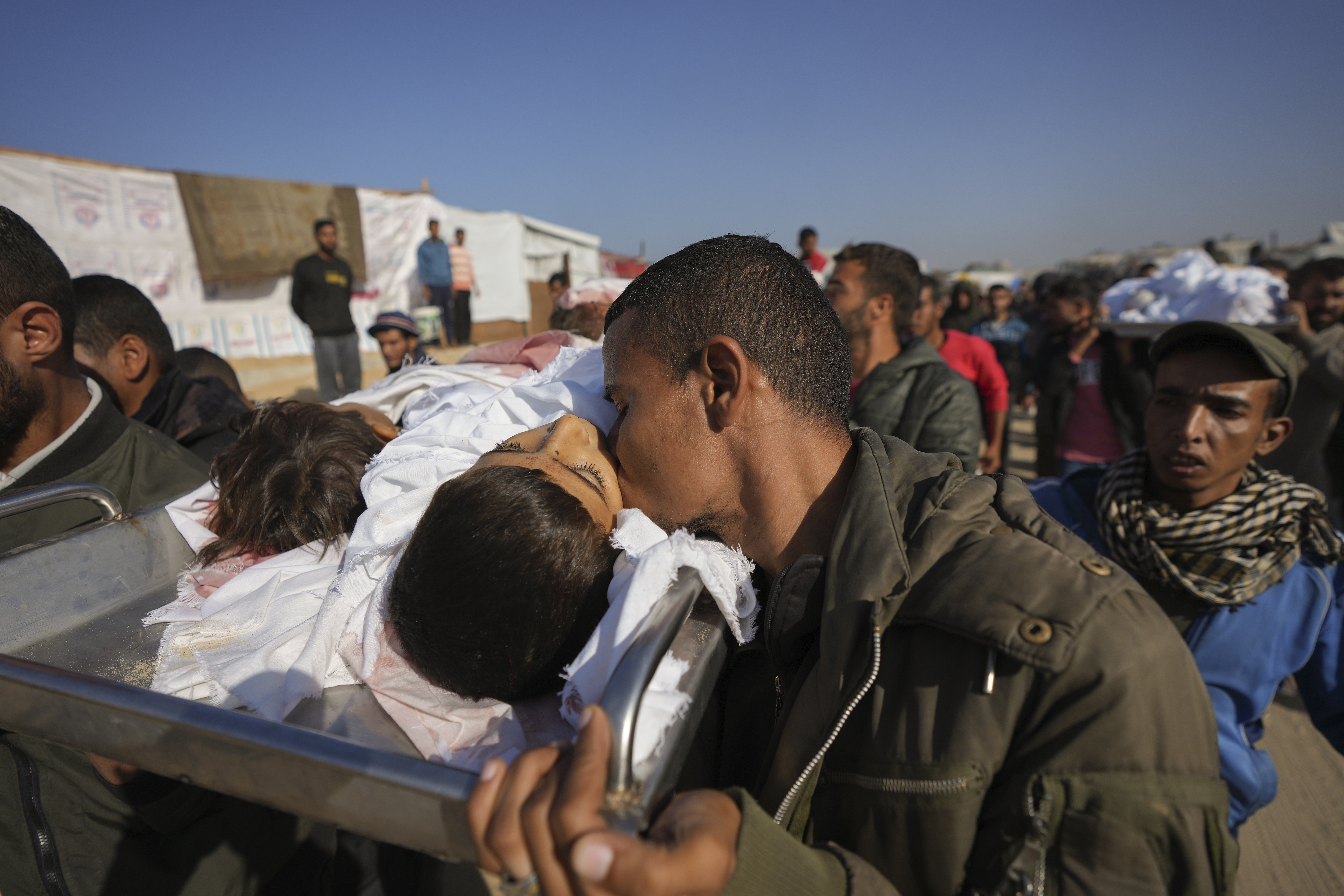 A man kisses the body one of three children as they are carried for burial in Khan Younis, Gaza Strip, Thursday Nov. 21, 2024. Seven-year-old Hamza, his five-year-old brother Abdelaziz, and his four-year-old sister Laila Hassan were among 9 people killed by an Israeli strike in Khan Younis on Wednesday. Palestinian health officials say the death toll in the Gaza Strip from the 13-month-old war between Israel and Hamas has surpassed 44,000. (AP Photo/Abdel Kareem Hana)