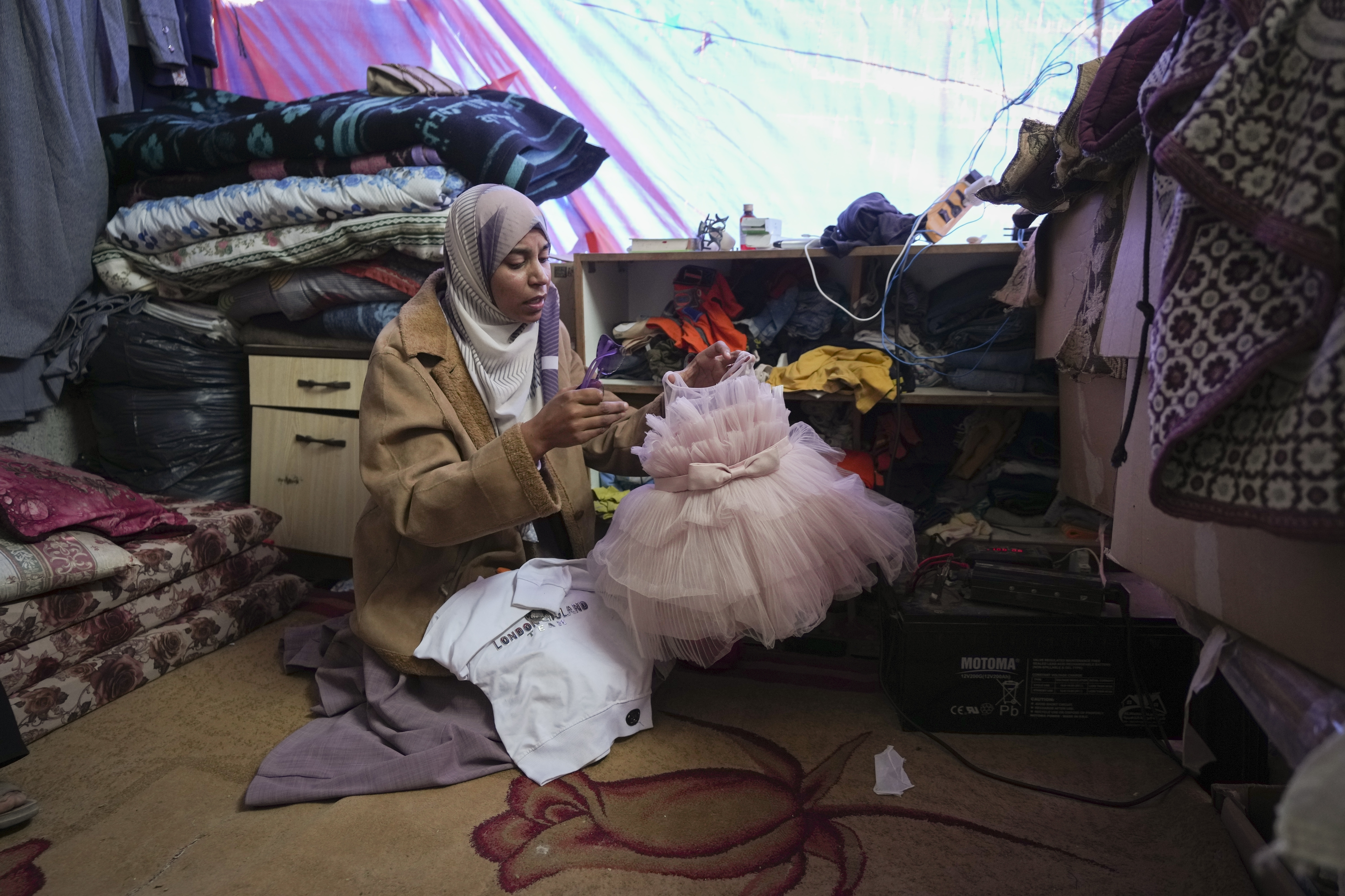 Areej al Qadi shows dress of her daughter Laila at her tent in a refugee camp in Khan Younis, Gaza Strip, Thursday Nov. 21, 2024. Seven-year-old Hamza, his five-year-old brother Abdelaziz, and his four-year-old sister Laila Hassan were among 9 people killed by an Israeli strike in Khan Younis on Wednesday. Palestinian health officials say the death toll in the Gaza Strip from the 13-month-old war between Israel and Hamas has surpassed 44,000. (AP Photo/Abdel Kareem Hana)