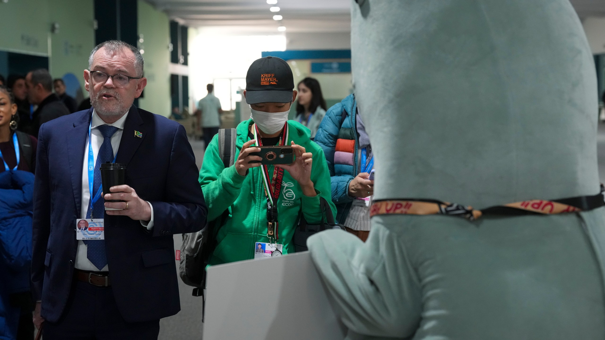 Dion George, South Africa environment minister, left, walks past a person in a dugong costume during the COP29 U.N. Climate Summit, Friday, Nov. 22, 2024, in Baku, Azerbaijan. (AP Photo/Peter Dejong)