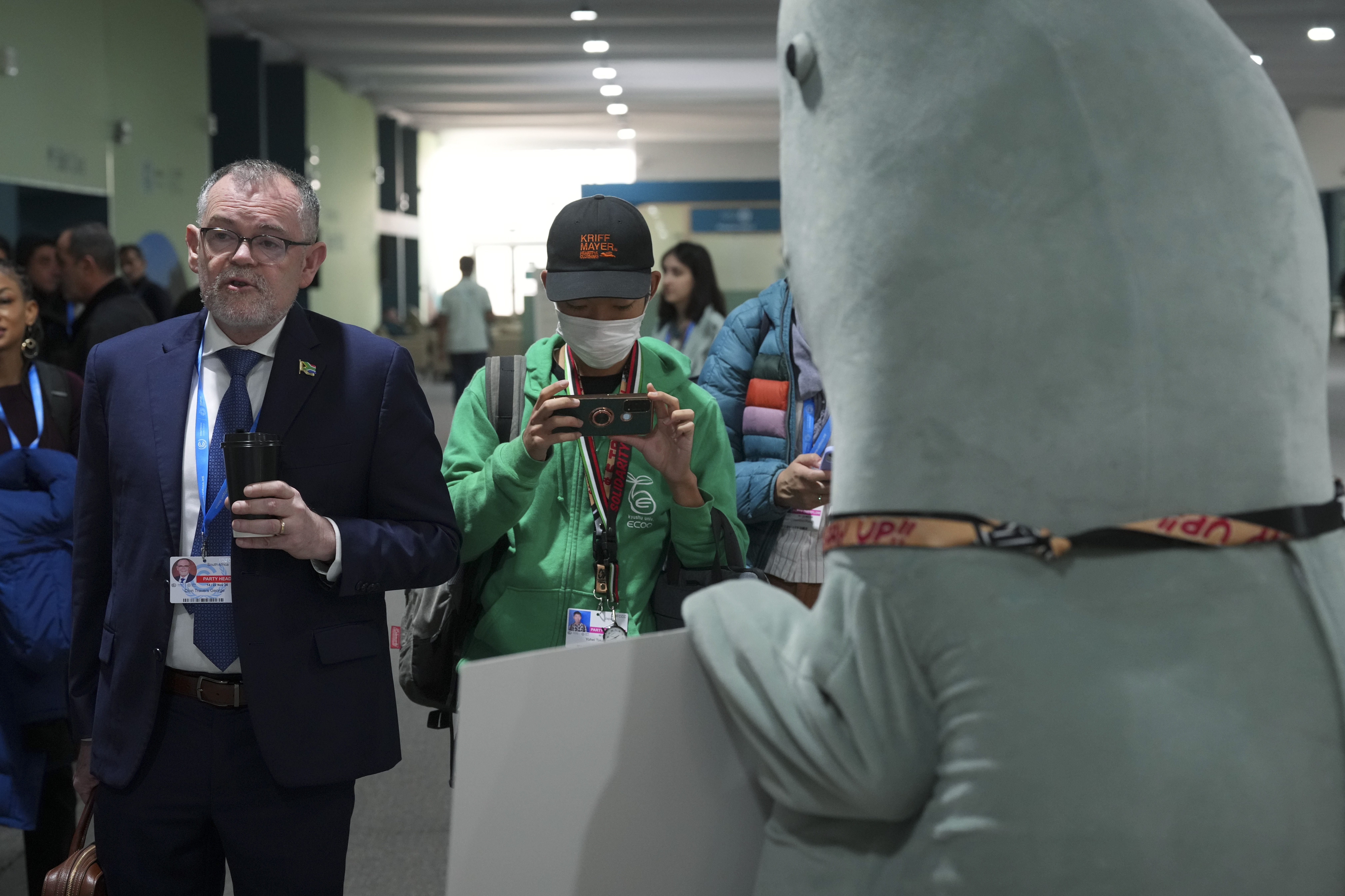 Dion George, South Africa environment minister, left, walks past a person in a dugong costume during the COP29 U.N. Climate Summit, Friday, Nov. 22, 2024, in Baku, Azerbaijan. (AP Photo/Peter Dejong)