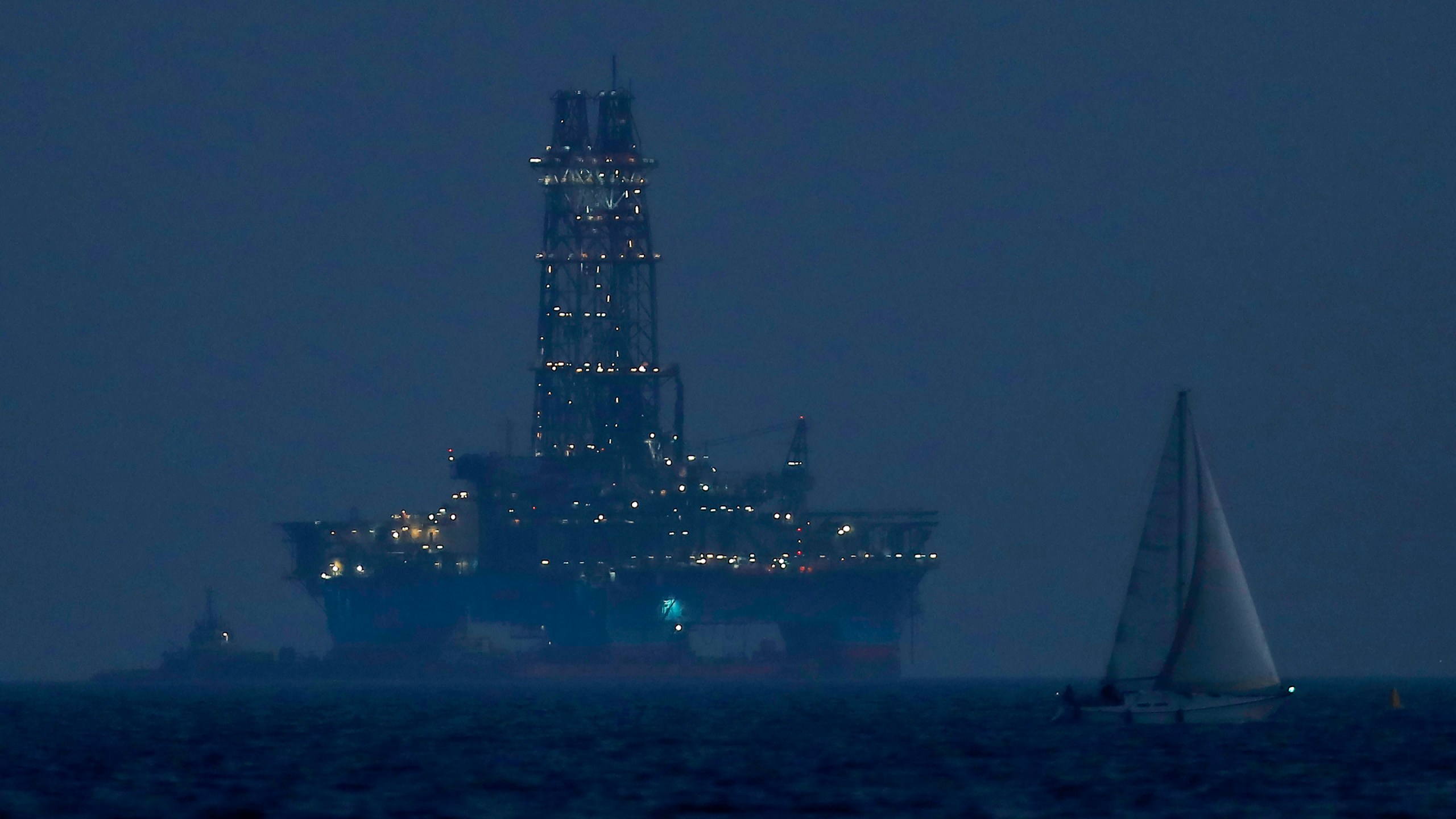 FILE - An offshore drilling rig is seen in the waters off Cyprus' coastal city of Limassol, on July 5, 2020 as a sailboat sails in the foreground. (AP Photo/Petros Karadjias, File)