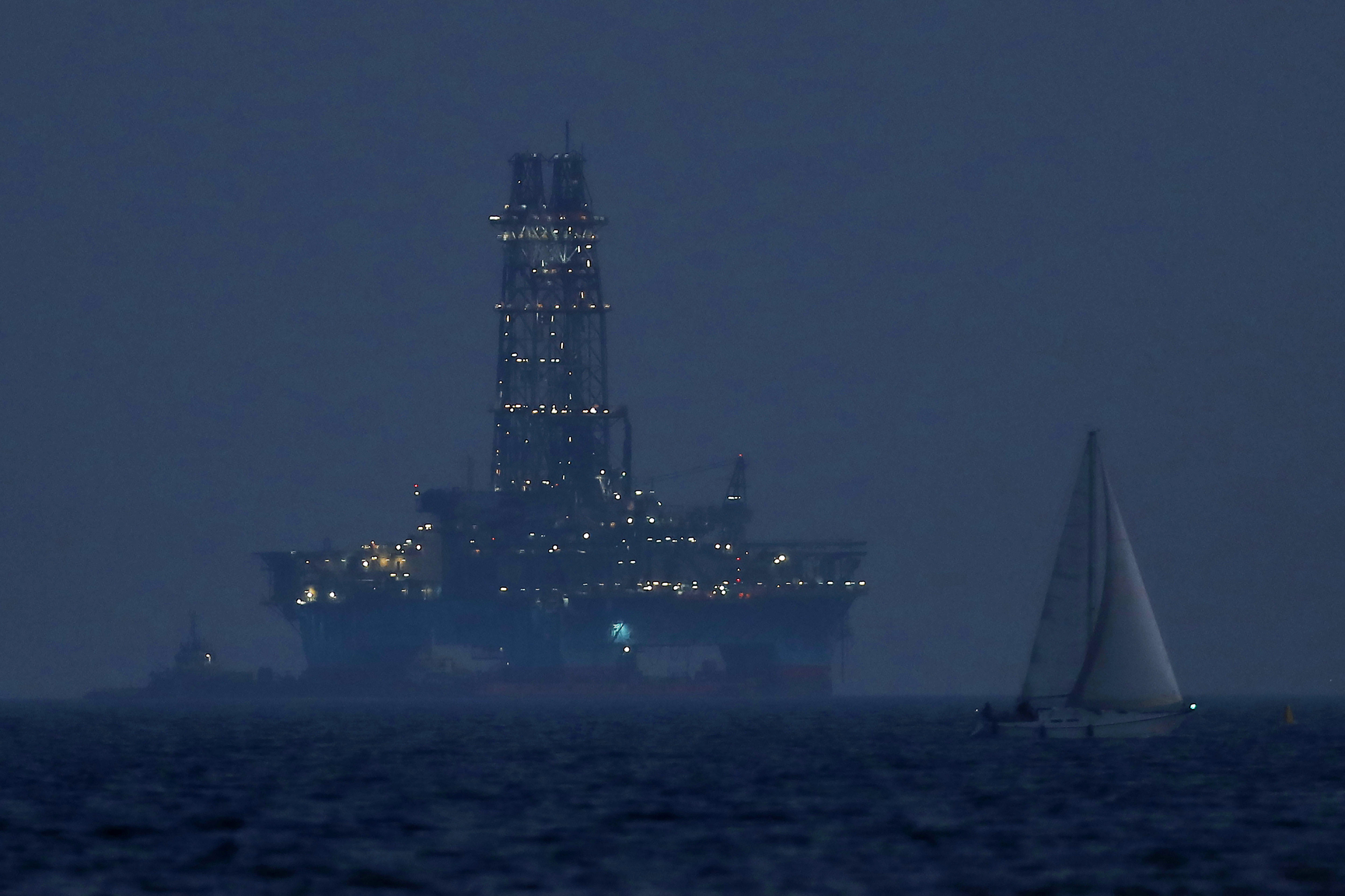 FILE - An offshore drilling rig is seen in the waters off Cyprus' coastal city of Limassol, on July 5, 2020 as a sailboat sails in the foreground. (AP Photo/Petros Karadjias, File)