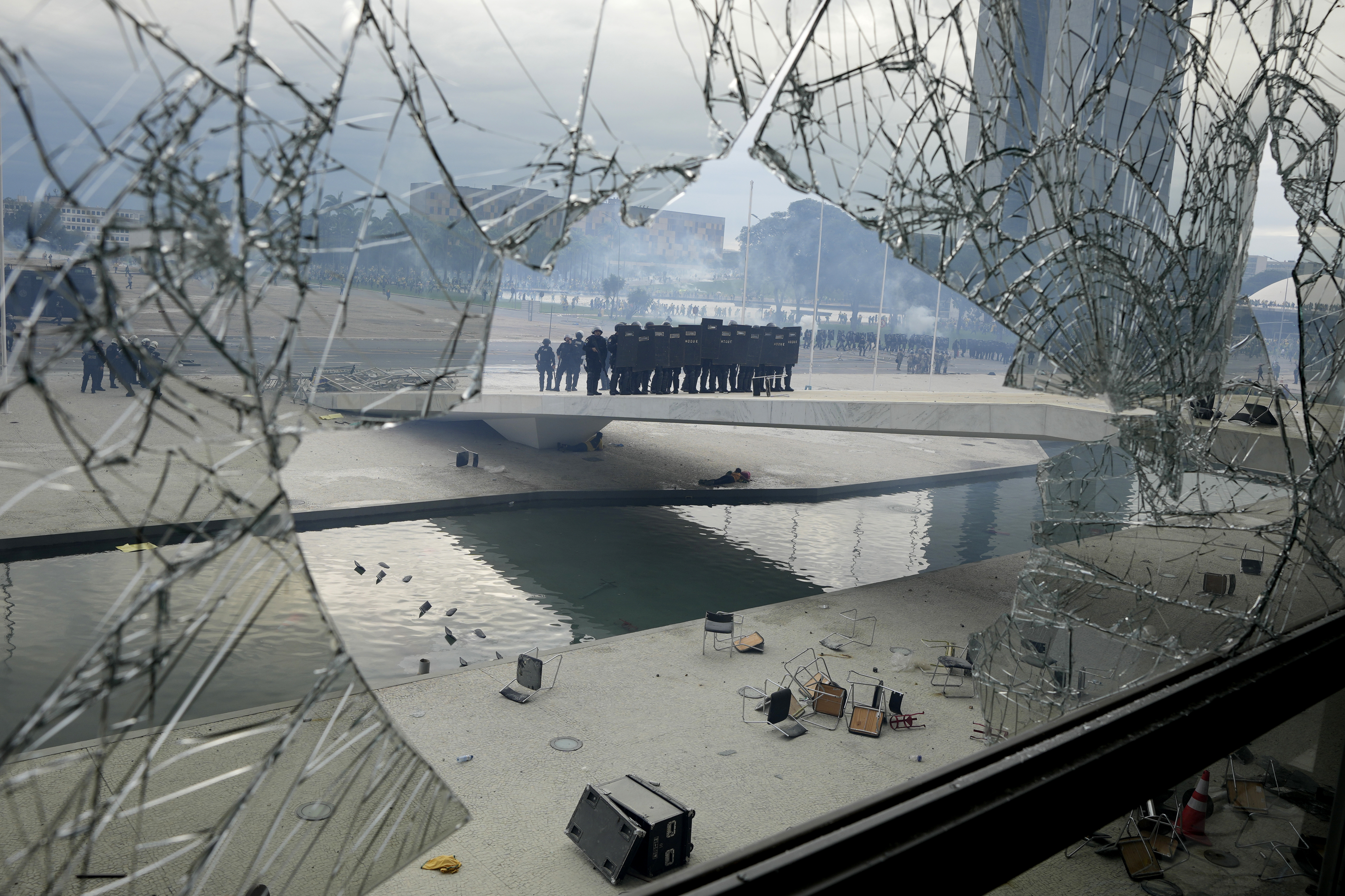 FILE - Police stand on the other side of a window at Planalto Palace that was shattered by supporters of Brazil's former President Jair Bolsonaro after they stormed the official workplace of the president in Brasilia, Brazil, Jan. 8, 2023. (AP Photo/Eraldo Peres, File)