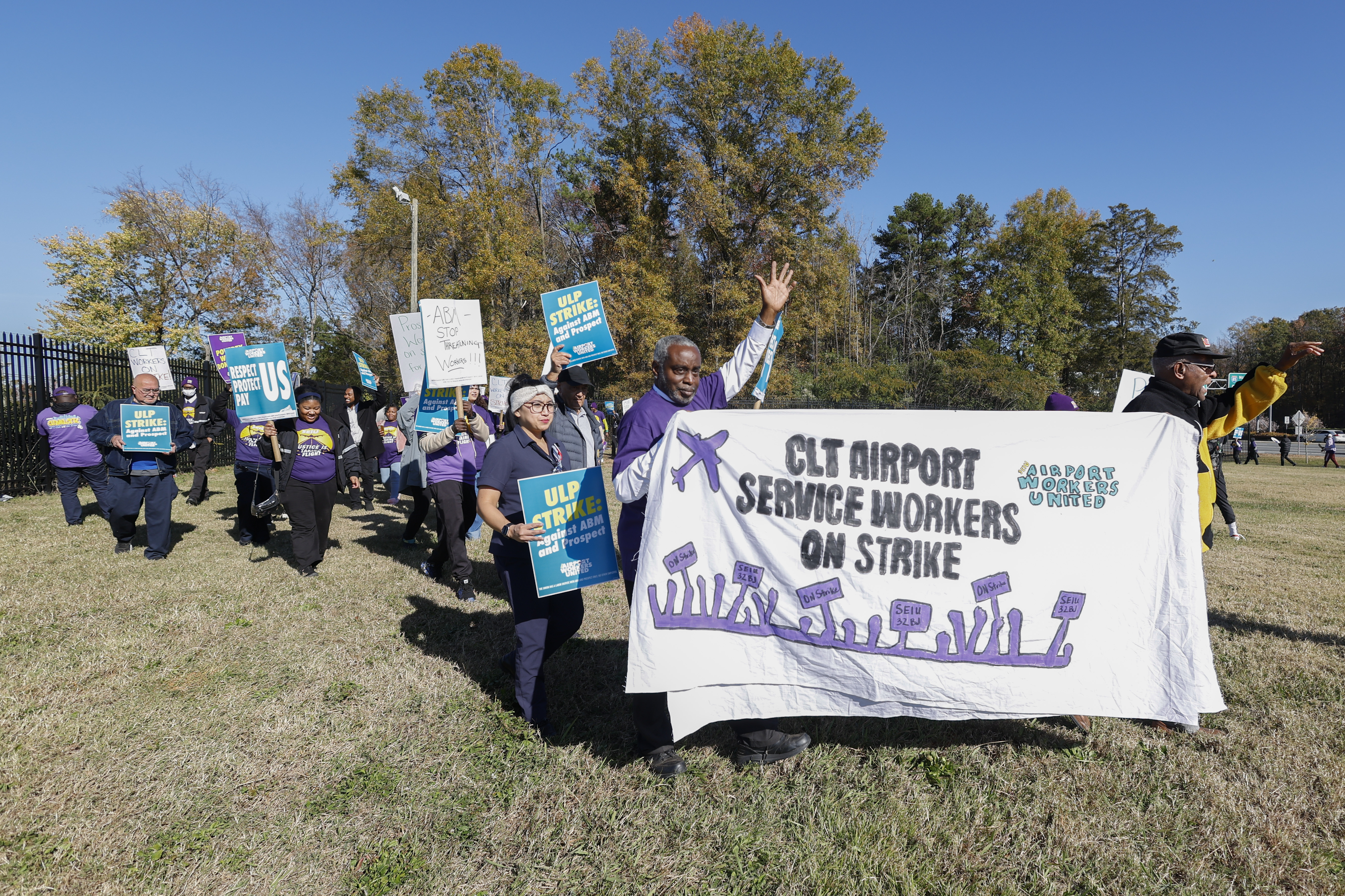 Airport workers wave signs as they march in front of the Charlotte Douglas International Airport in Charlotte, N.C., Monday, Nov. 25, 2024. (AP Photo/Nell Redmond)