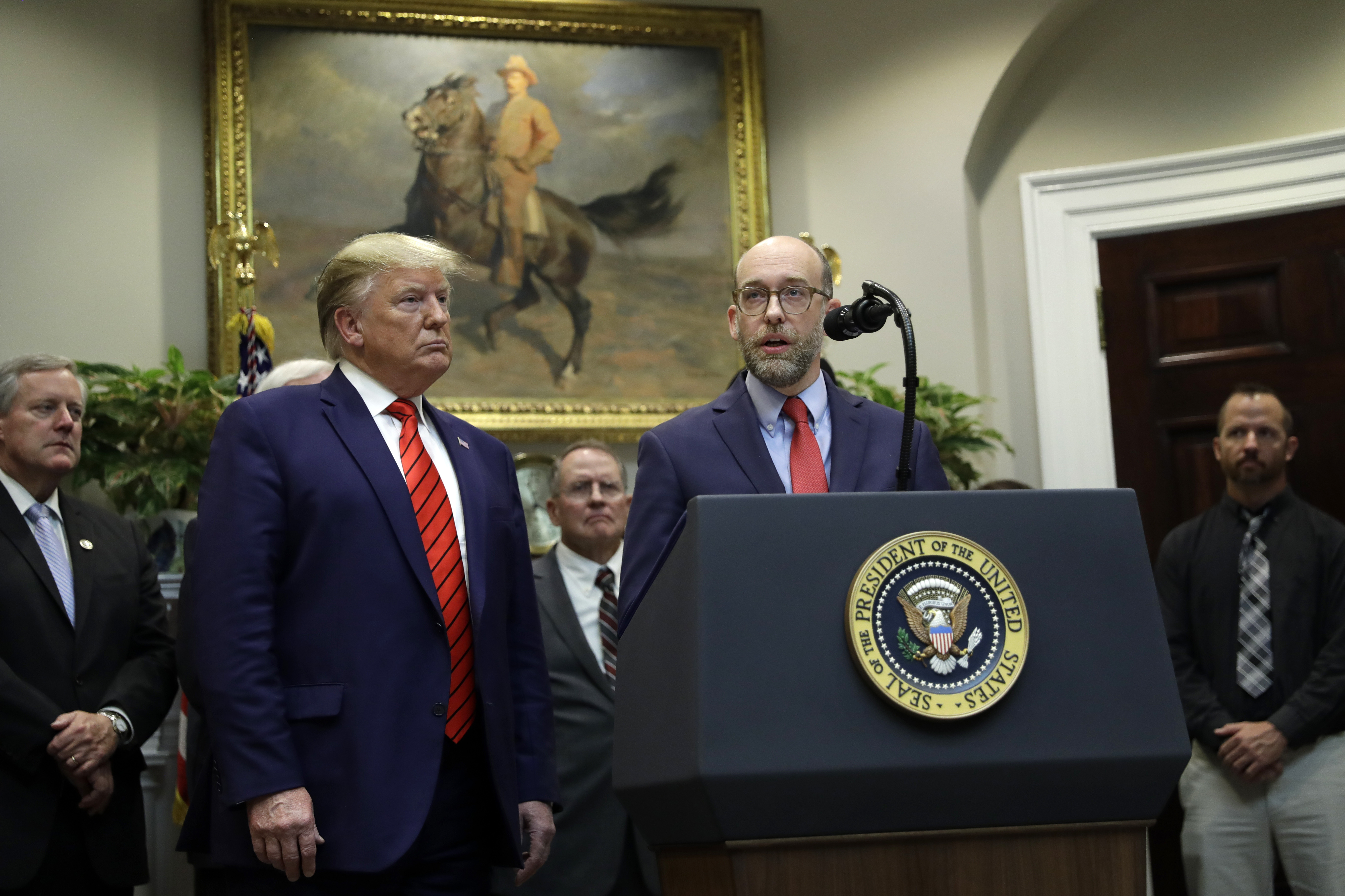 FILE - President Donald Trump, left, listens as acting director of the Office of Management and Budget Russel Vought speaks during an event on "transparency in Federal guidance and enforcement" in the Roosevelt Room of the White House, Oct. 9, 2019, in Washington. (AP Photo/Evan Vucci, File)