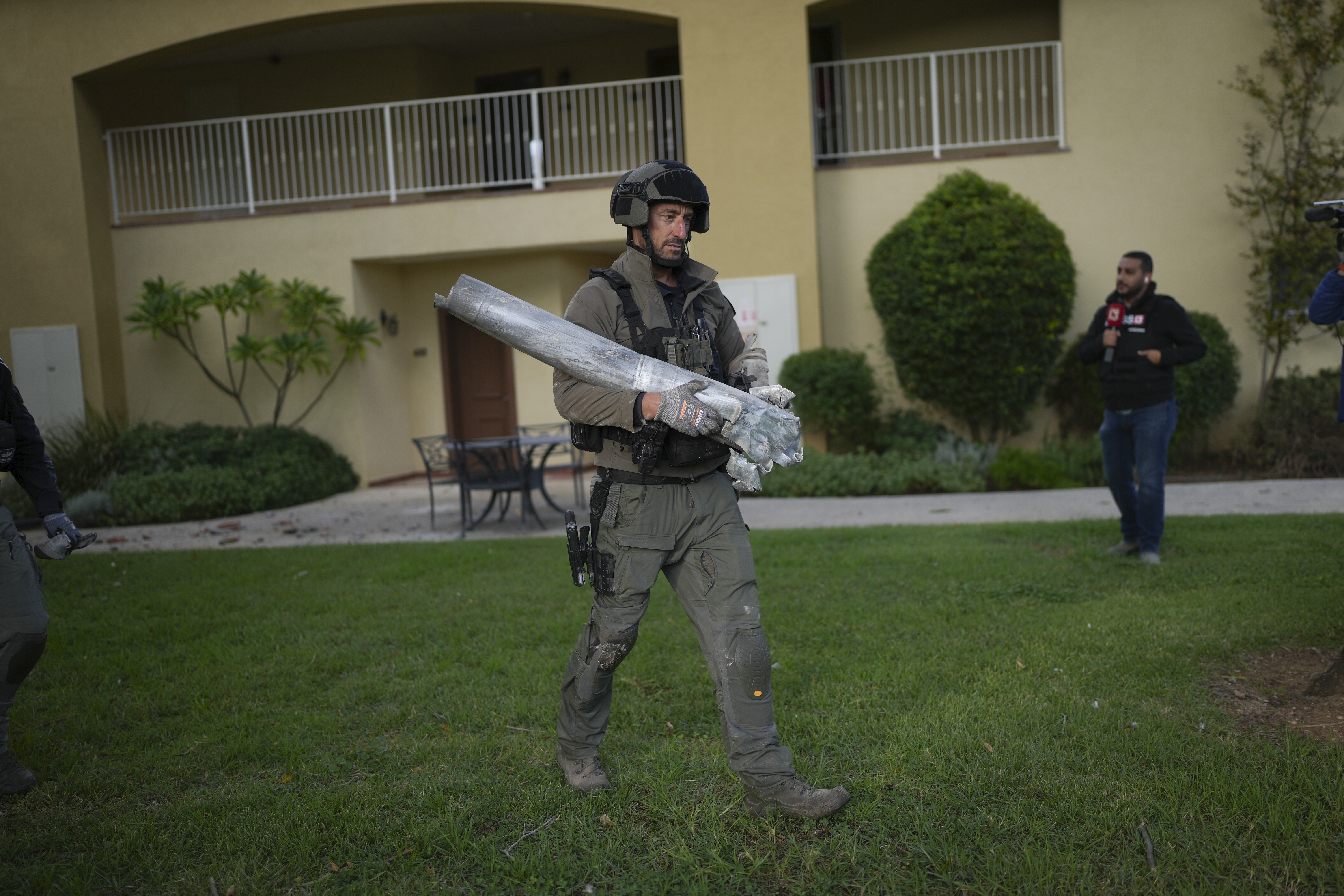 An Israeli bomb squad police officer carries the remains of a rocket that was fired from Lebanon in Kibbutz Kfar Blum, northern Israel Sunday Nov. 24, 2024. (AP Photo/Ohad Zwigenberg)