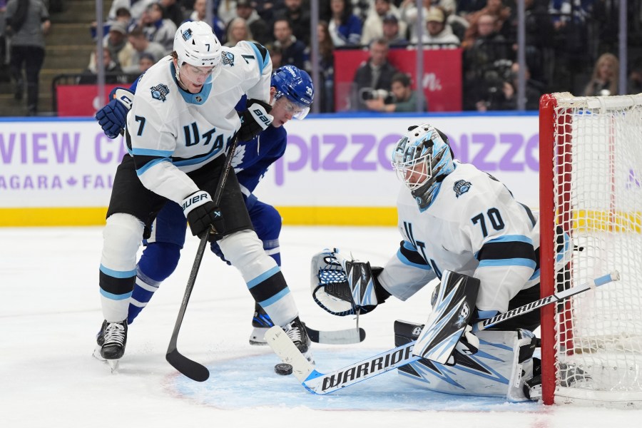 Utah Hockey Club goaltender Karel Vejmelka (70) makes a save as defenceman Michael Kesselring (7) and Toronto Maple Leafs centre Fraser Minten (39) battle for a rebound during the second period of an NHL hockey game in Toronto, Sunday, Nov. 24, 2024. (Frank Gunn/The Canadian Press via AP)