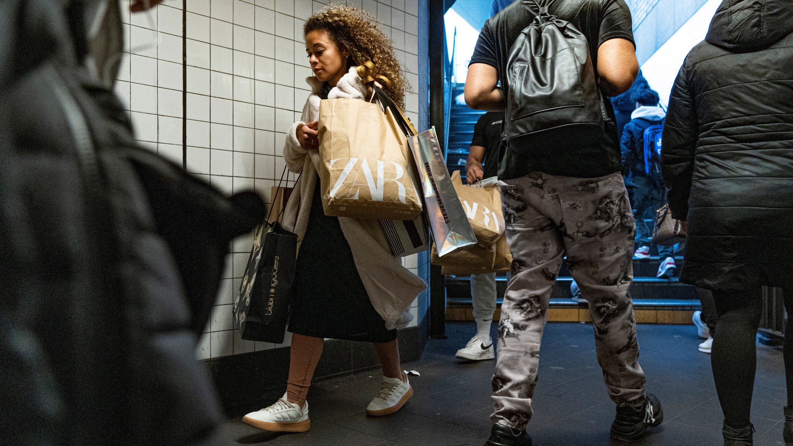 FILE - A woman carrying shopping bags enters the Broadway-Lafayette Street subway station on Black Friday in New York, Nov. 24, 2023. (AP Photo/Peter K. Afriyie, File)