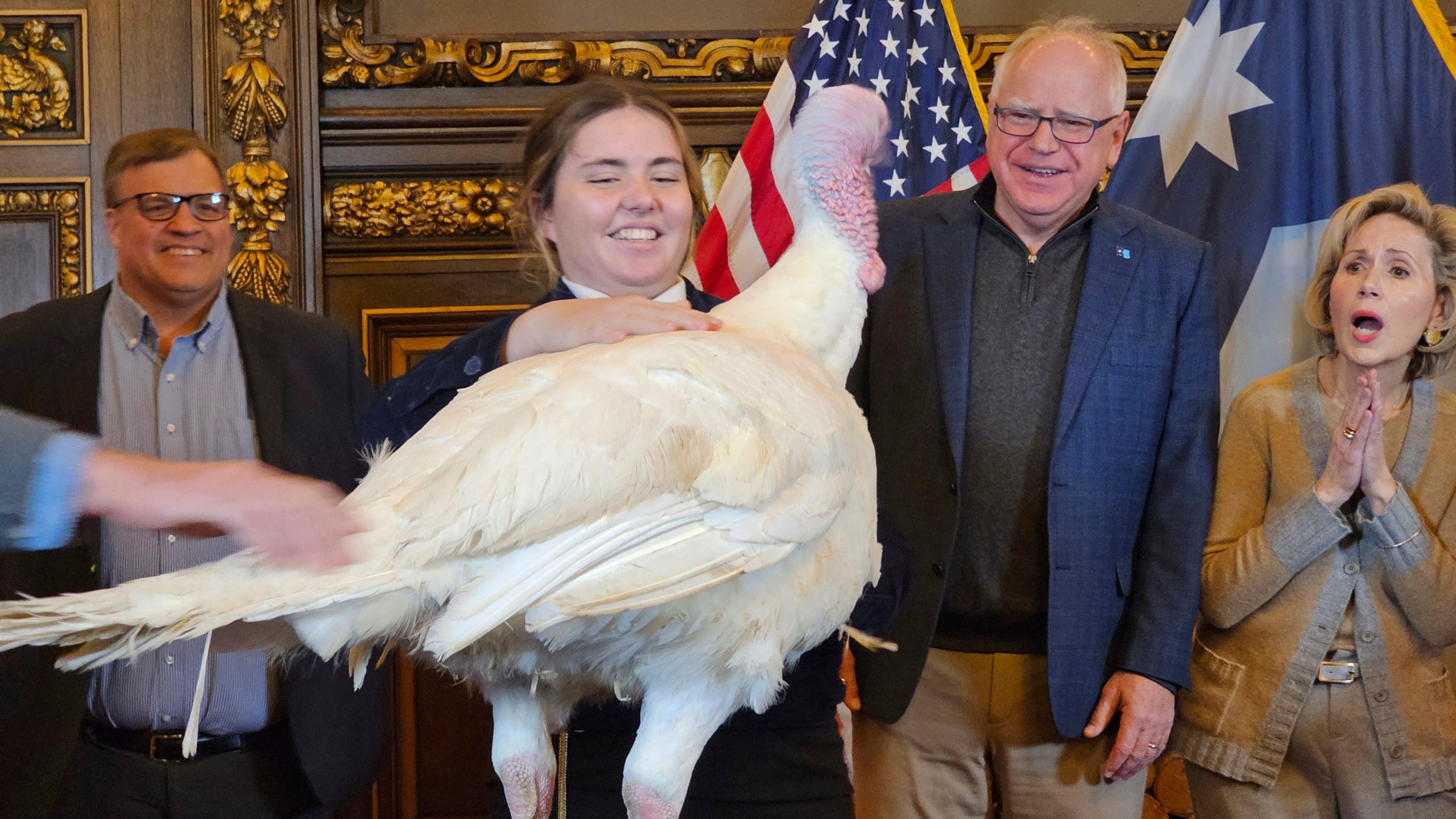 Gov. Tim Walz, second right, accepts the symbolic presentation of a turkey from Paisley VonBerge, a Future Farmers of America leader from Hutchinson, at the Minnesota State Capitol on Tuesday, Nov. 26, 2024, as state Agriculture Commissioner Thom Petersen and first lady Gwen Walz look on. (AP Photo/Steve Karnowski)