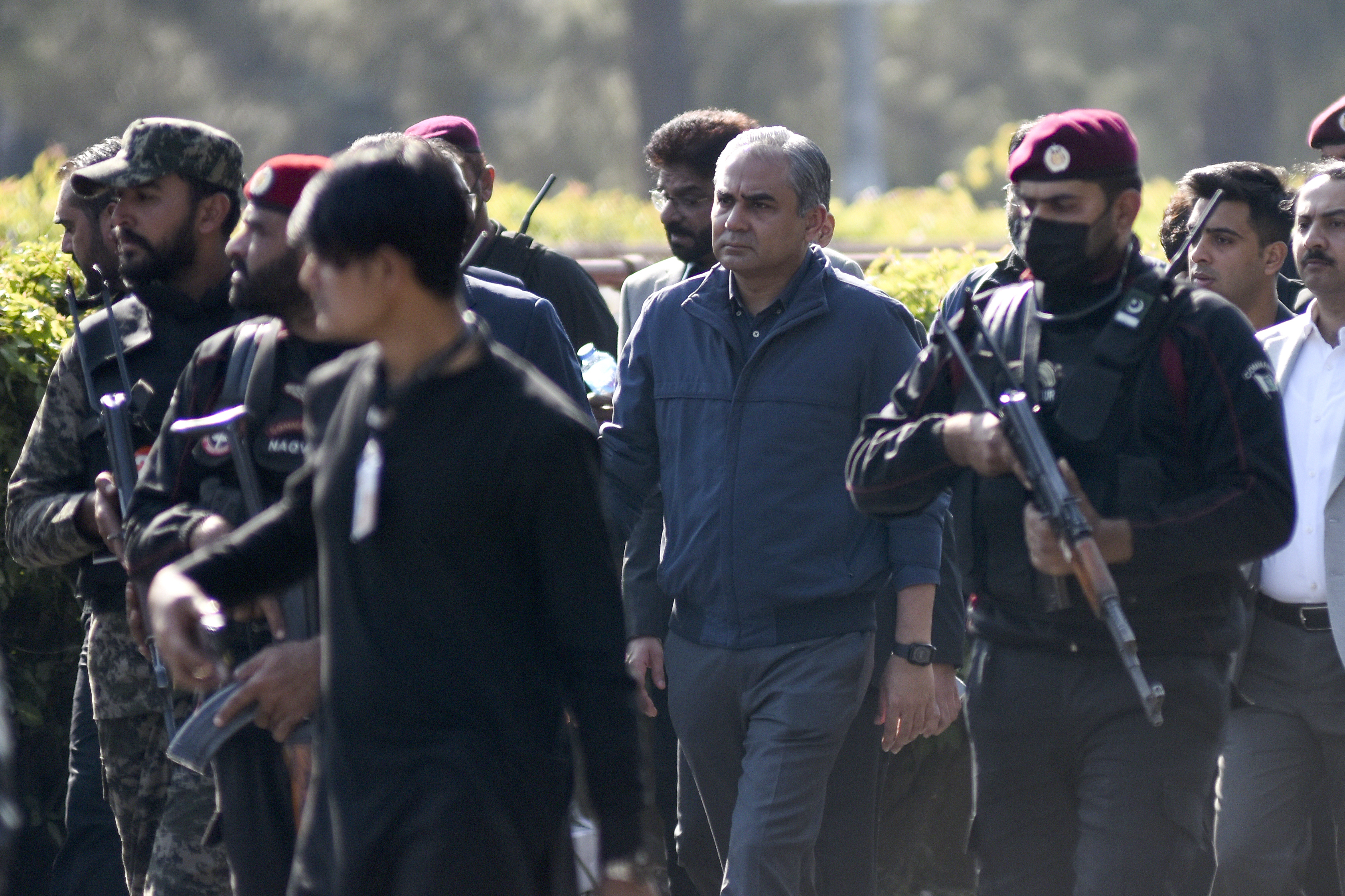 Security officials escort Pakistan's Interior Minister Mohsin Naqvi, center, who arrives to talk with media regarding current situation at D-Chowk square close to Red Zone, which is an area that houses key government buildings in Islamabad, Pakistan, Tuesday, Nov. 26, 2024. (AP Photo/W.K. Yousufzai)