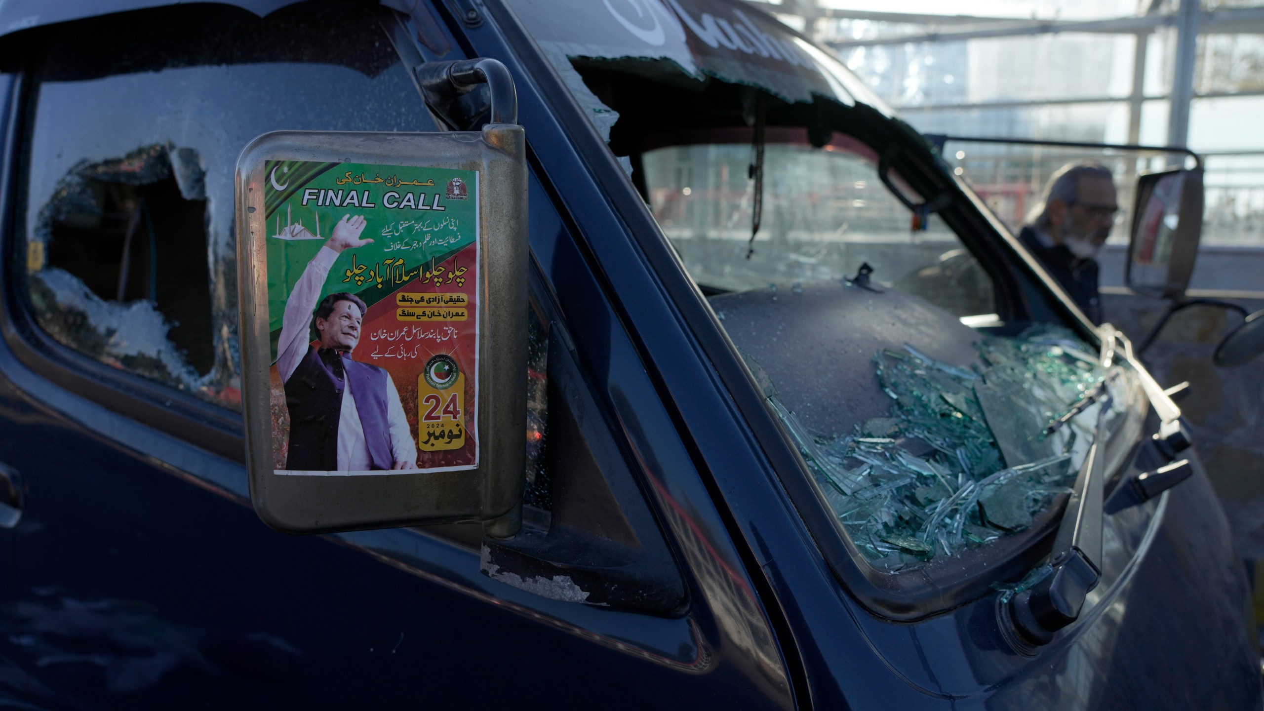 A poster of imprisoned former premier Imran Khan is displayed on a damaged vehicle left behind by supporters of Khan's Pakistan Tehreek-e-Insaf party after clashes with security forces the night before, in Islamabad, Pakistan, Wednesday, Nov. 27, 2024. (AP Photo/Anjum Naveed)