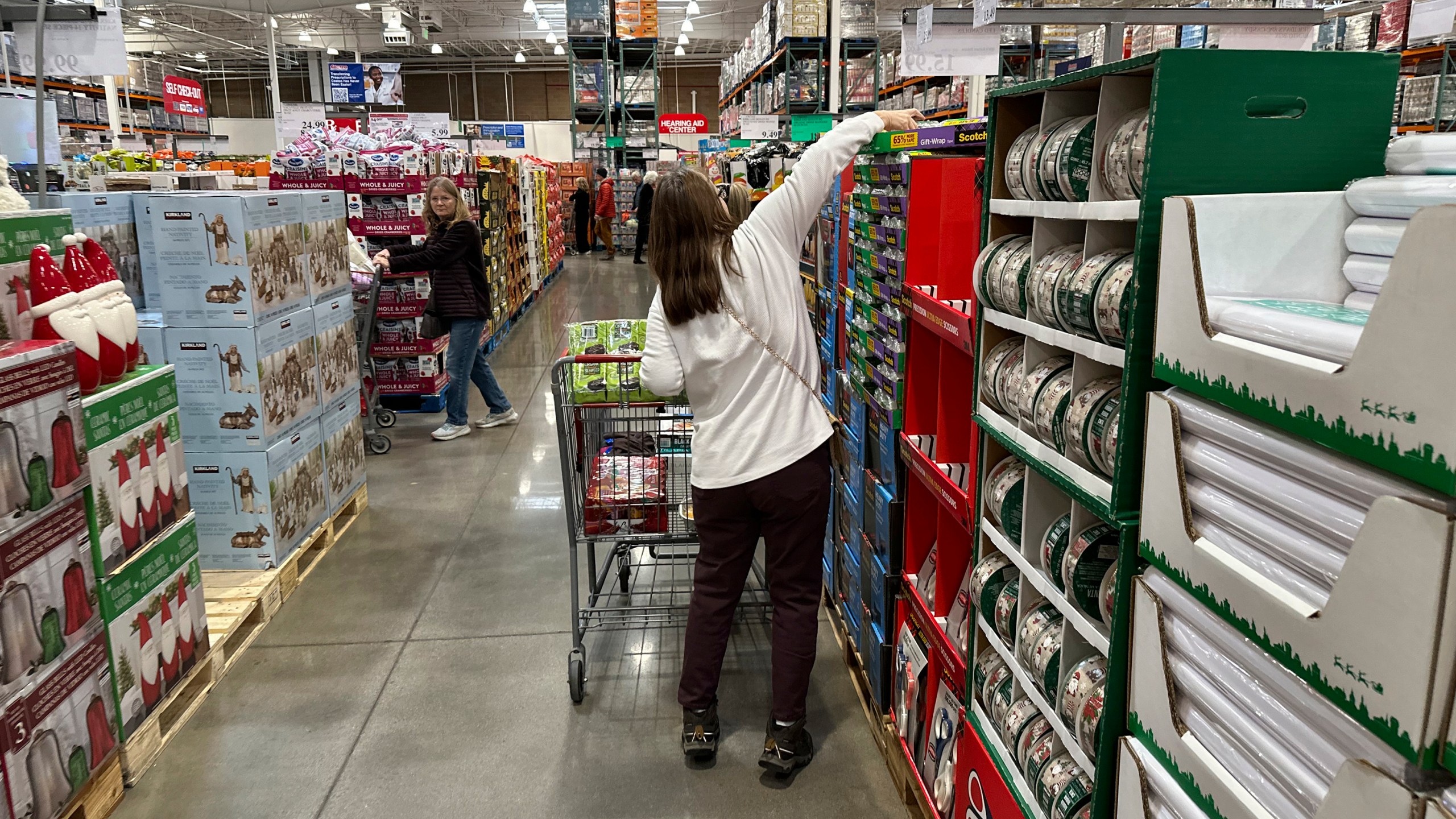 FILE - Shoppers reach for items on display in a Costco warehouse Nov. 19, 2024, in Lone Tree, Colo. (AP Photo/David Zalubowski, File)