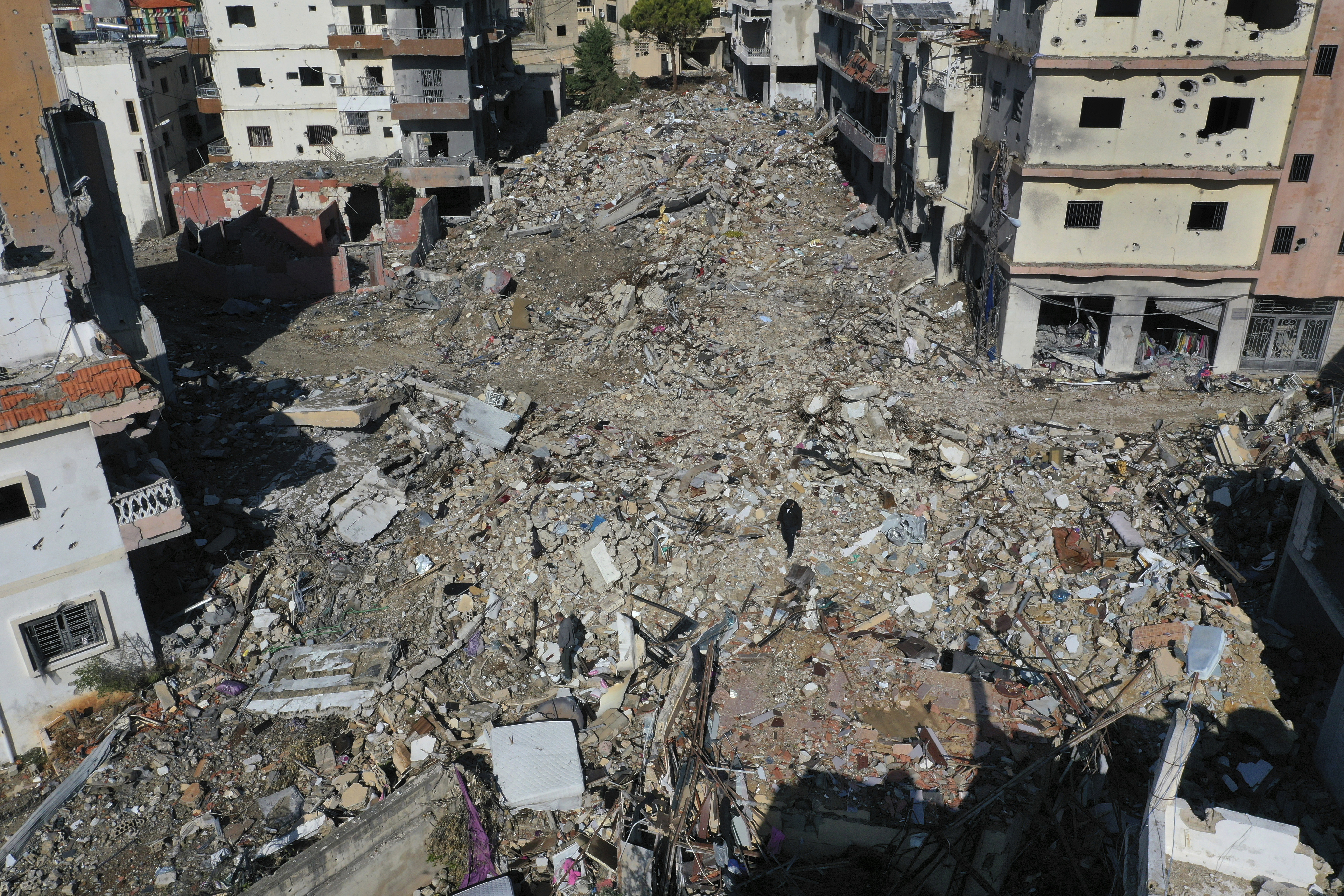 Residents walk on the rubble of destroyed buildings after they returned to Qana village, southern Lebanon, Thursday, Nov. 28, 2024 following a ceasefire between Israel and Hezbollah that went into effect on Wednesday.(AP Photo/Hussein Malla)