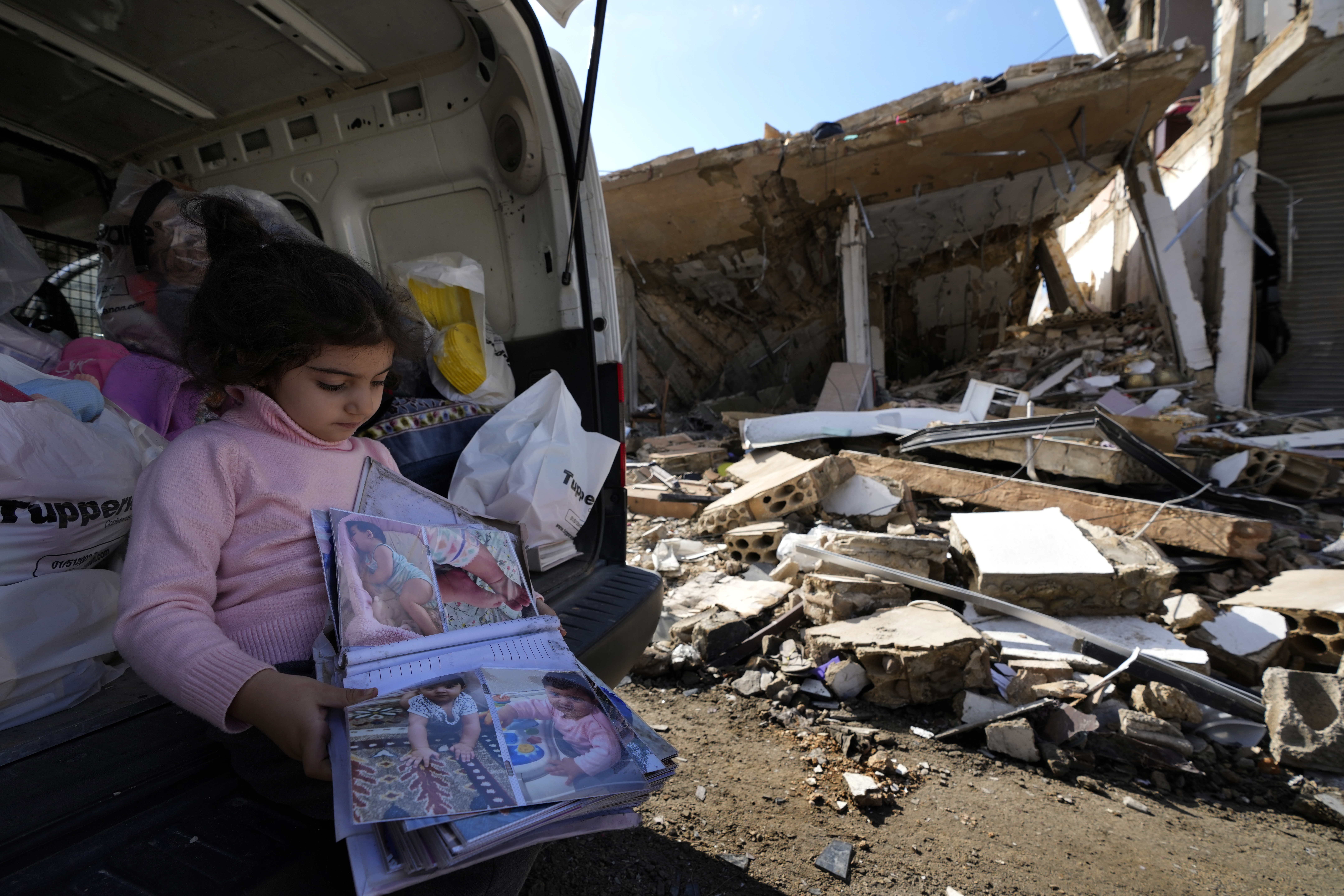 Yara Srour, 4, holds her photo album, as she sits in front of her grandparents destroyed house after she returned with her family to Hanouiyeh village, southern Lebanon, Thursday, Nov. 28, 2024 following a ceasefire between Israel and Hezbollah that went into effect on Wednesday.(AP Photo/Hussein Malla)