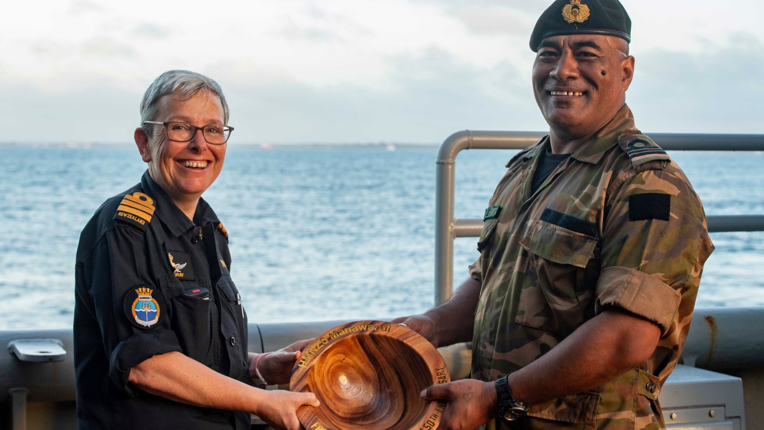 FILE - In this undated photo provided by the New Zealand Defence Force, Lieutenant Commander Tala Mafile'o of the Royal Tongan Navy presents Commander Yvonne Gray, left, with a carved wooden bowl as a memento of the RNZN's participation in the 50th Anniversary Fleet Review. (New Zealand Defence Force via AP,File)