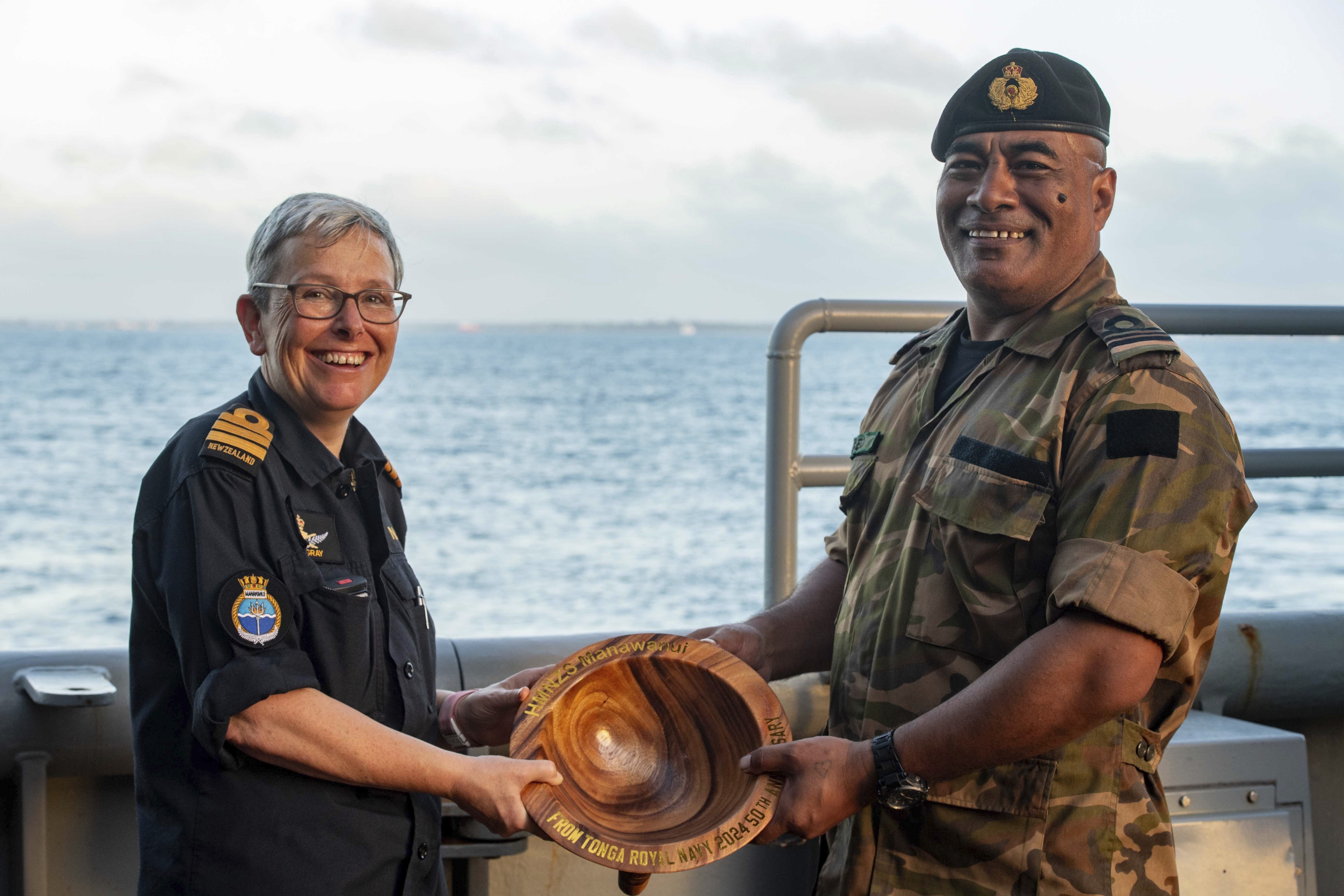 FILE - In this undated photo provided by the New Zealand Defence Force, Lieutenant Commander Tala Mafile'o of the Royal Tongan Navy presents Commander Yvonne Gray, left, with a carved wooden bowl as a memento of the RNZN's participation in the 50th Anniversary Fleet Review. (New Zealand Defence Force via AP,File)