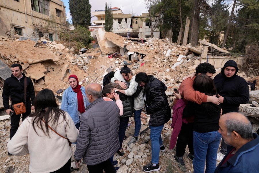 Displaced residents hug as they stand in front of the rubble of their destroyed house in Baalbek, eastern Lebanon, Thursday, Nov. 28, 2024. (AP Photo/Hassan Ammar)