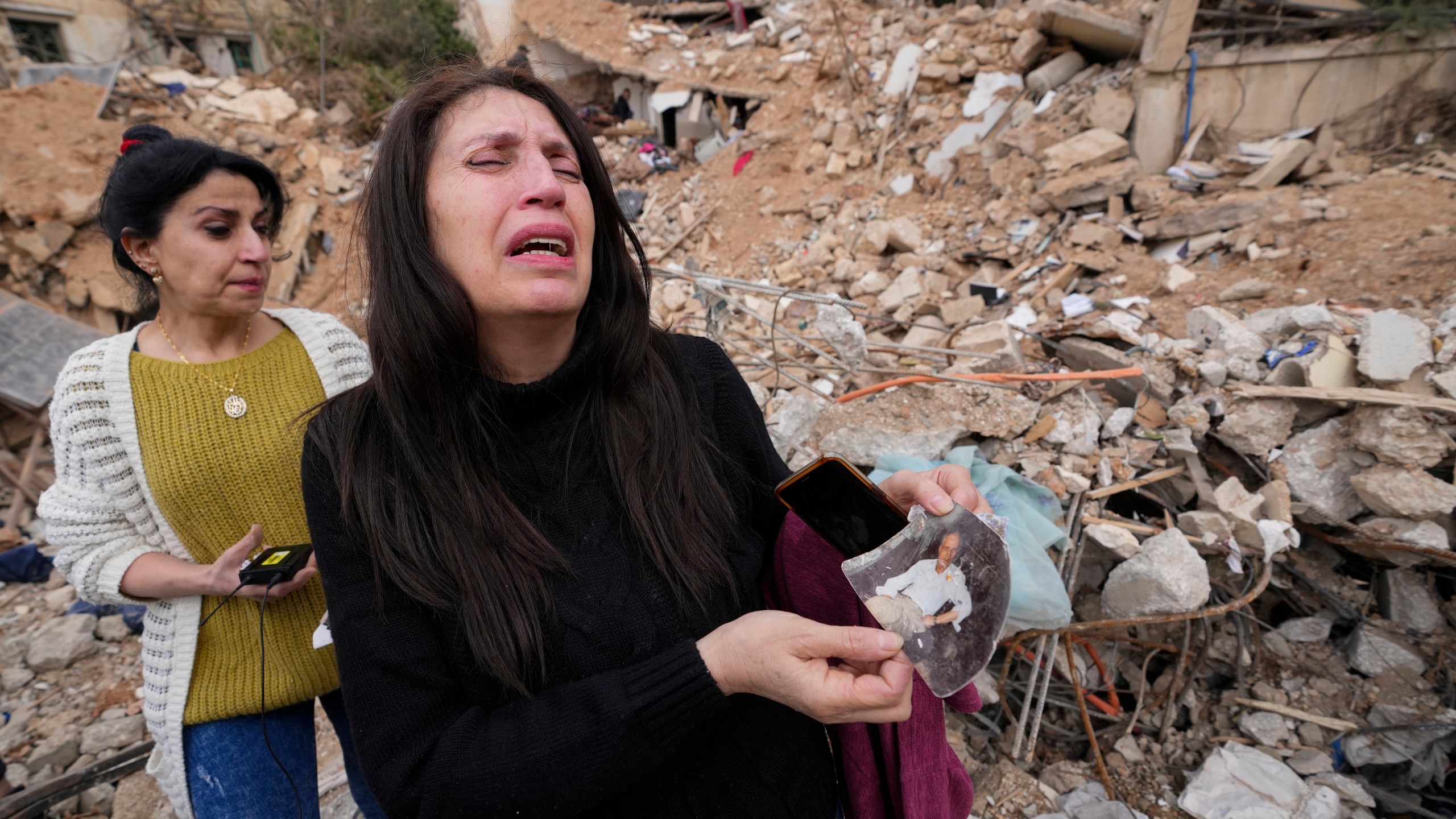 Zeina Rida Jawhari, reacts after recovering a photo of her father from the rubble of her destroyed house in Baalbek, eastern Lebanon, Thursday, Nov. 28, 2024. (AP Photo/Hassan Ammar)