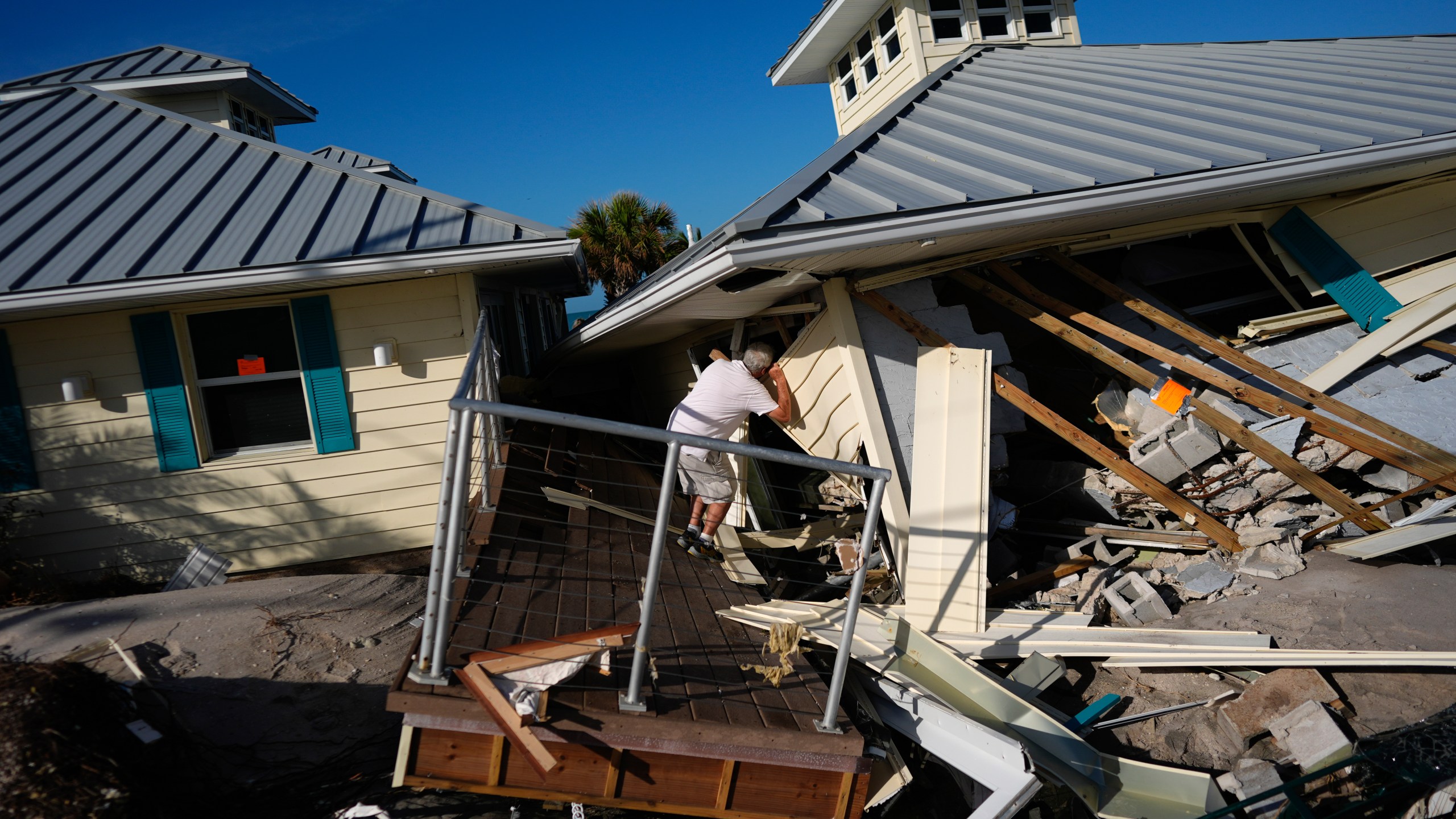 FILE - A property owner who preferred not to give his name peers into the remains of the second floor unit where he lived with his wife while renting out the other units, on Manasota Key, in Englewood, Fla., following the passage of Hurricane Milton, Oct. 13, 2024. (AP Photo/Rebecca Blackwell, File)