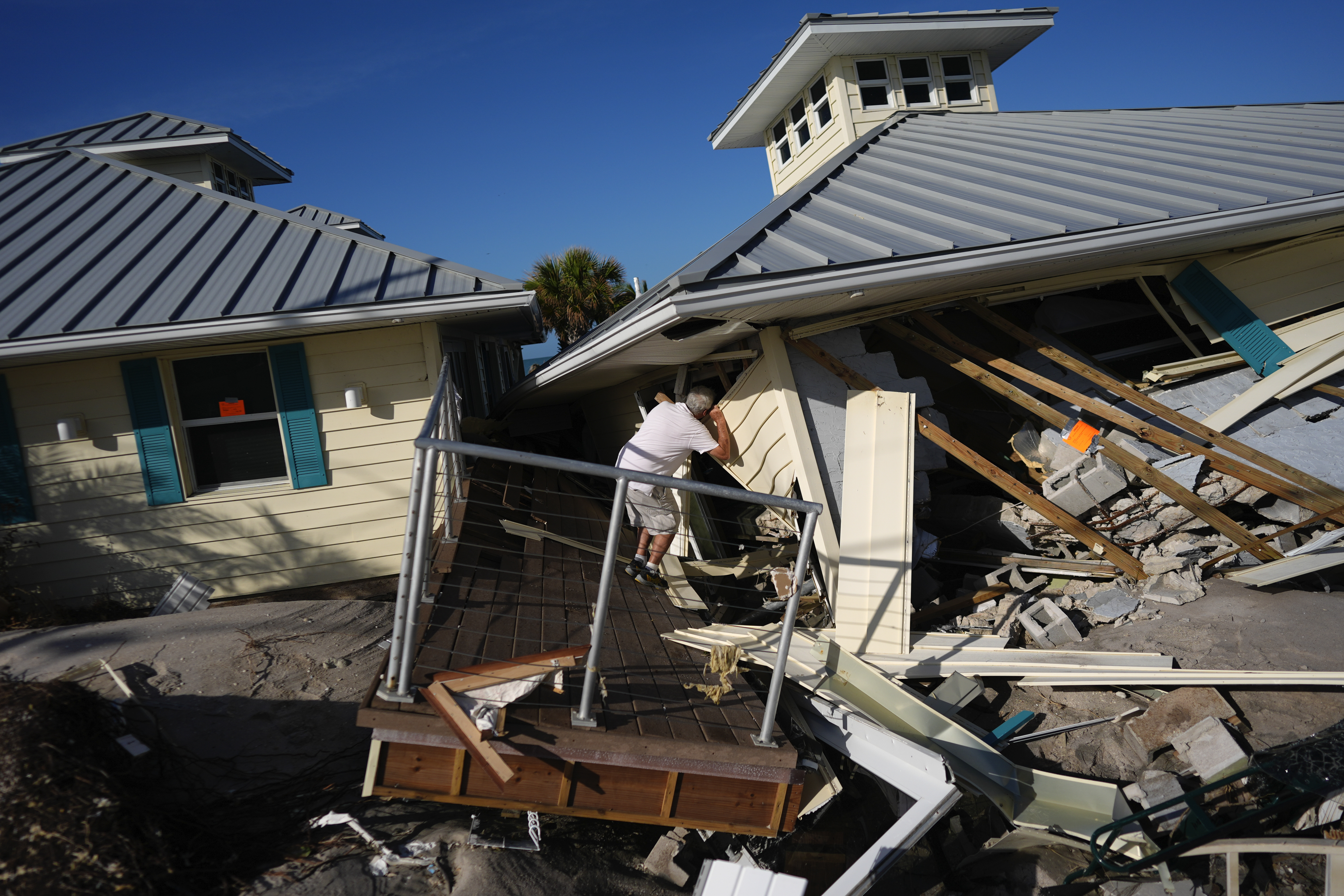 FILE - A property owner who preferred not to give his name peers into the remains of the second floor unit where he lived with his wife while renting out the other units, on Manasota Key, in Englewood, Fla., following the passage of Hurricane Milton, Oct. 13, 2024. (AP Photo/Rebecca Blackwell, File)