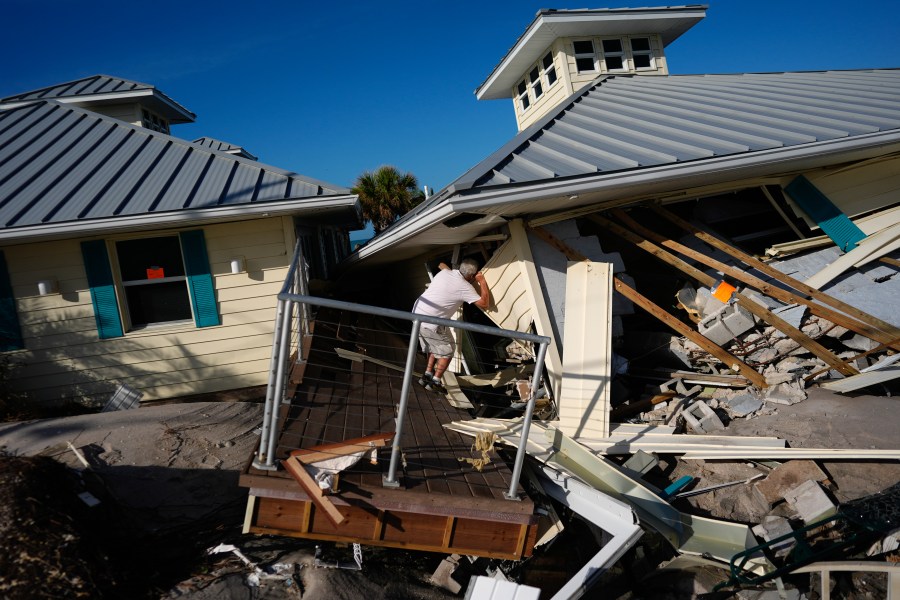 FILE - A property owner who preferred not to give his name peers into the remains of the second floor unit where he lived with his wife while renting out the other units, on Manasota Key, in Englewood, Fla., following the passage of Hurricane Milton, Oct. 13, 2024. (AP Photo/Rebecca Blackwell, File)