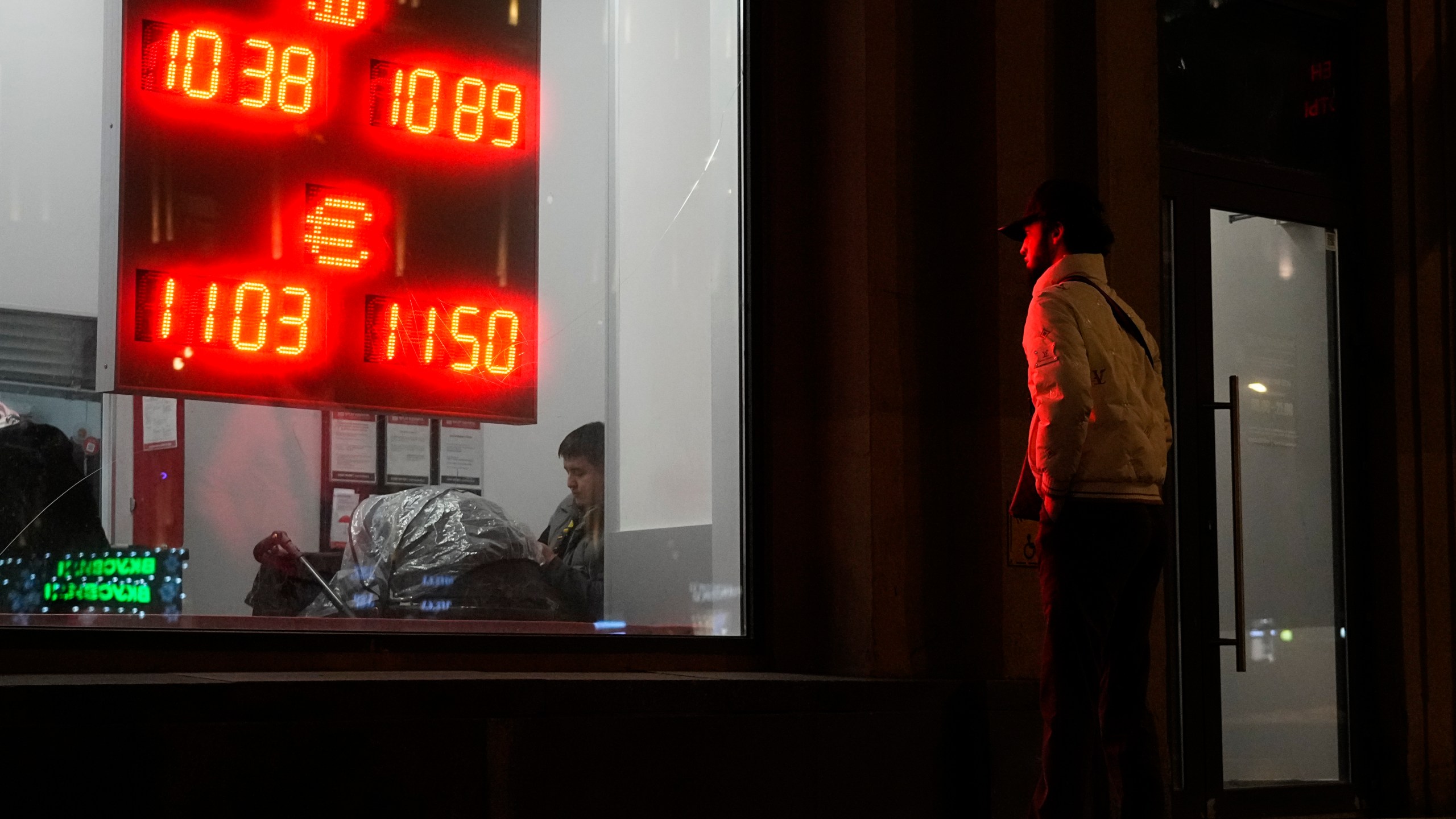 A man watches at an exchange office sign showing the currency exchange rates of the Russian ruble, U.S. dollar, and euro in Moscow, Russia, Thursday, Nov. 28, 2024. (AP Photo/Pavel Bednyakov)