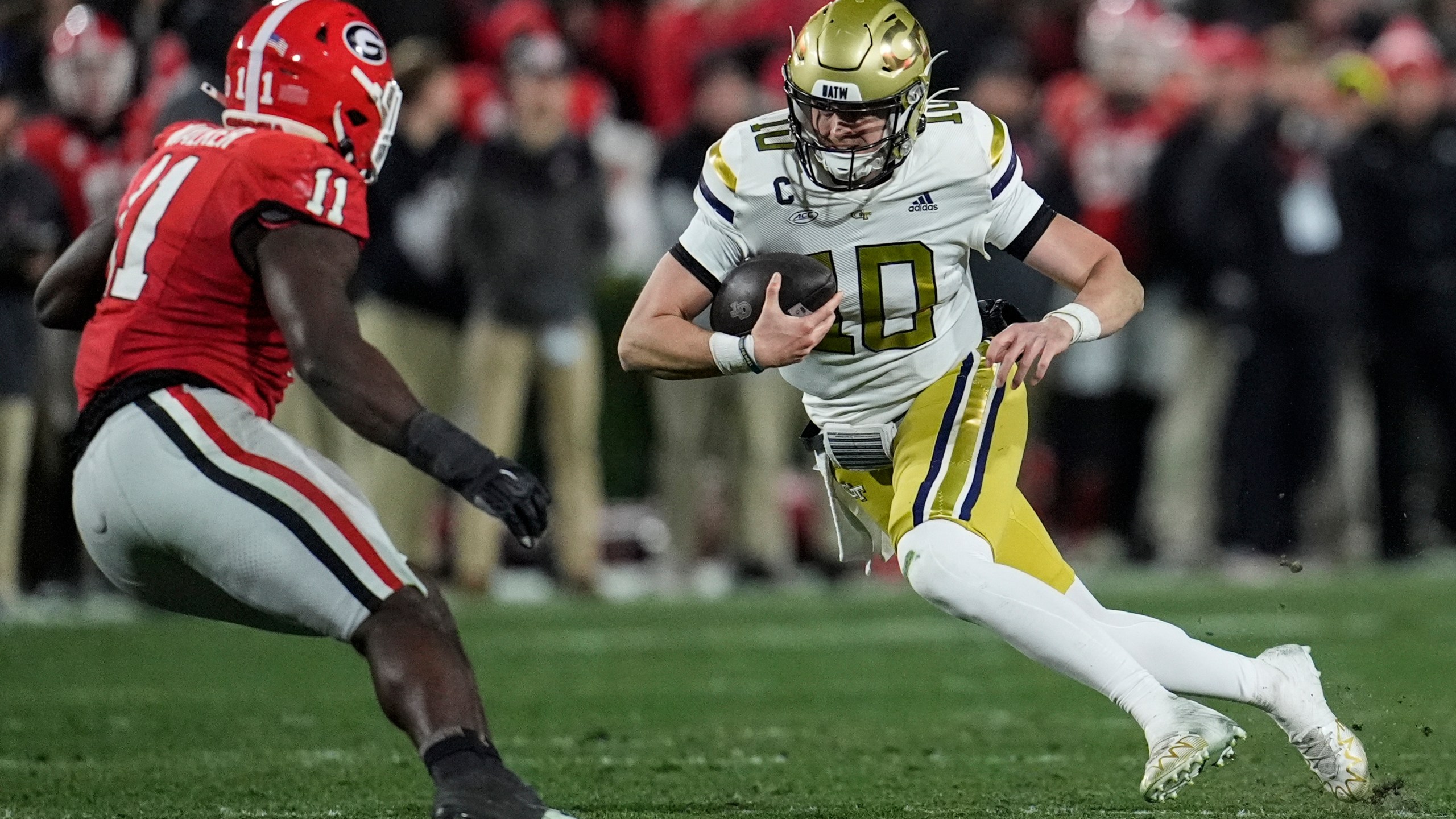 Georgia Tech quarterback Haynes King (10) runs against Georgia linebacker Jalon Walker (11) during the first half of an NCAA college football game, Friday, Nov. 29, 2024, in Athens, Ga. (AP Photo/Mike Stewart)