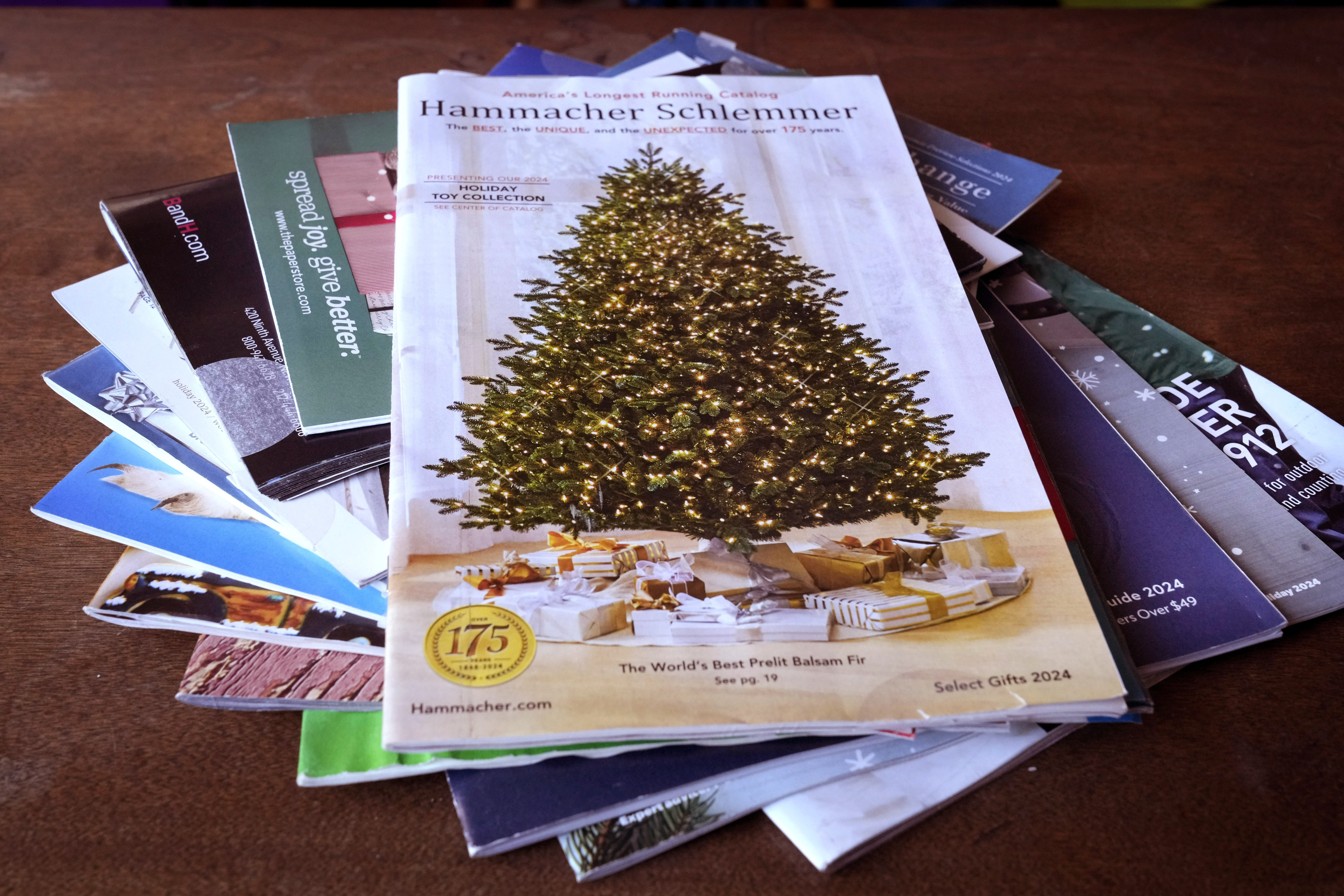 A collection of 2024 holiday catalogs are displayed Monday, Nov. 25, 2024, in Freeport, Maine. Catalog retailers, reeling from U.S. postal rate increases, have responded with pint-sized catalogs this holiday season. (AP Photo/Robert F. Bukaty)