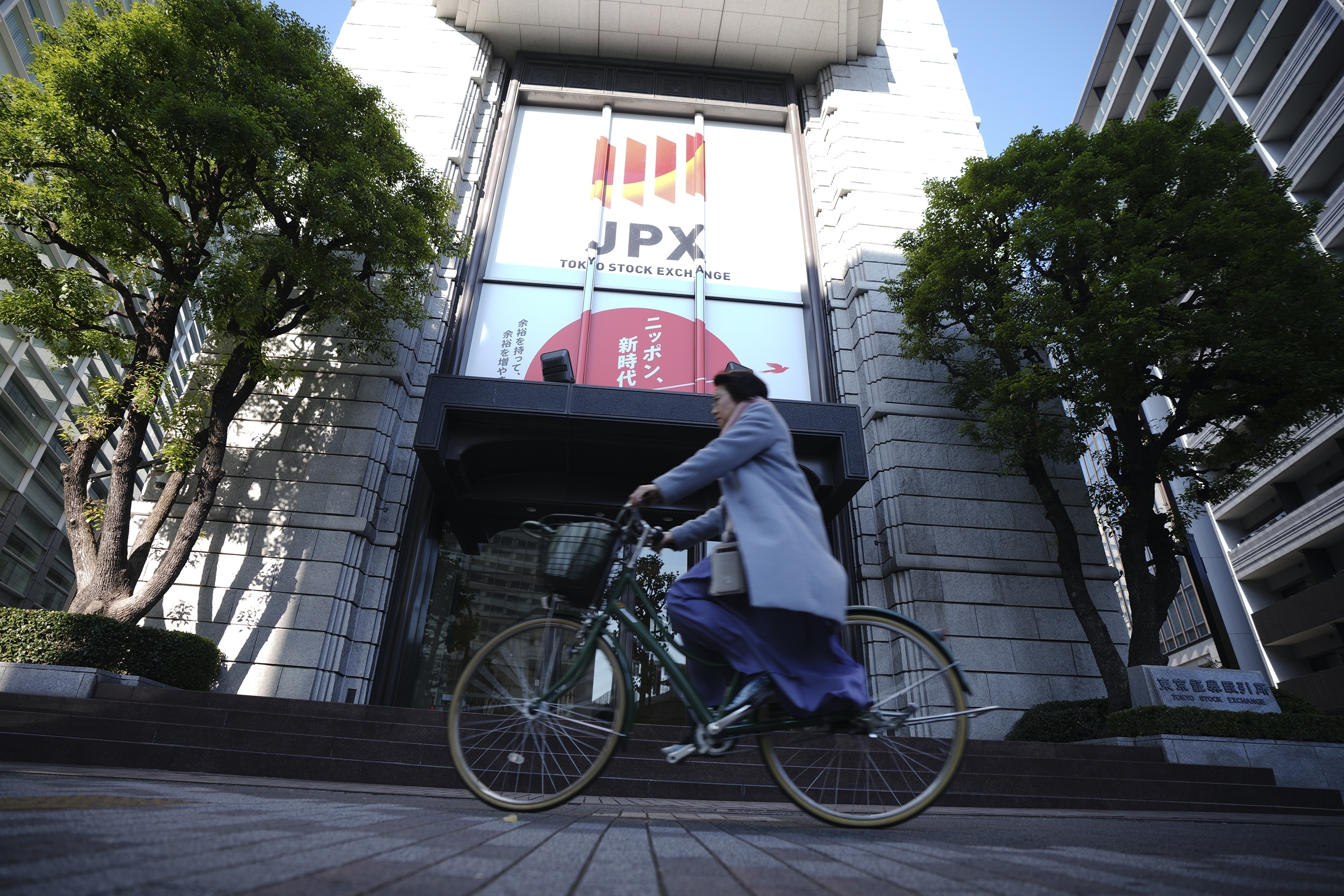 A person rides a bicycle in front of Tokyo Stock Exchange building Tuesday, Dec. 3, 2024, in Tokyo. (AP Photo/Eugene Hoshiko)