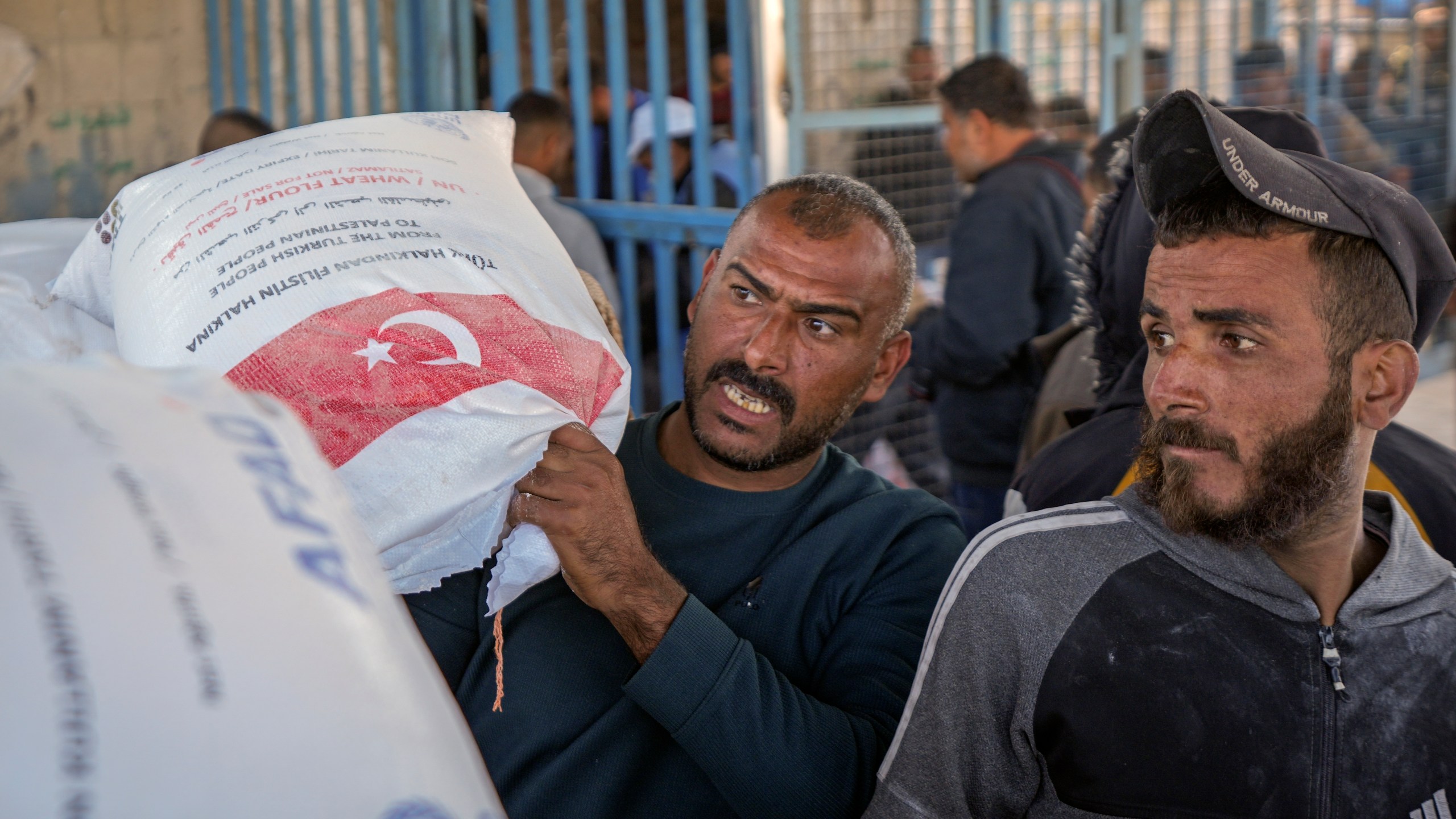 A man grabs a sack of donated flour at a UNRWA distribution center in the Nuseirat refugee camp, Gaza Strip, Tuesday Dec. 3, 2024.(AP Photo/Abdel Kareem Hana)