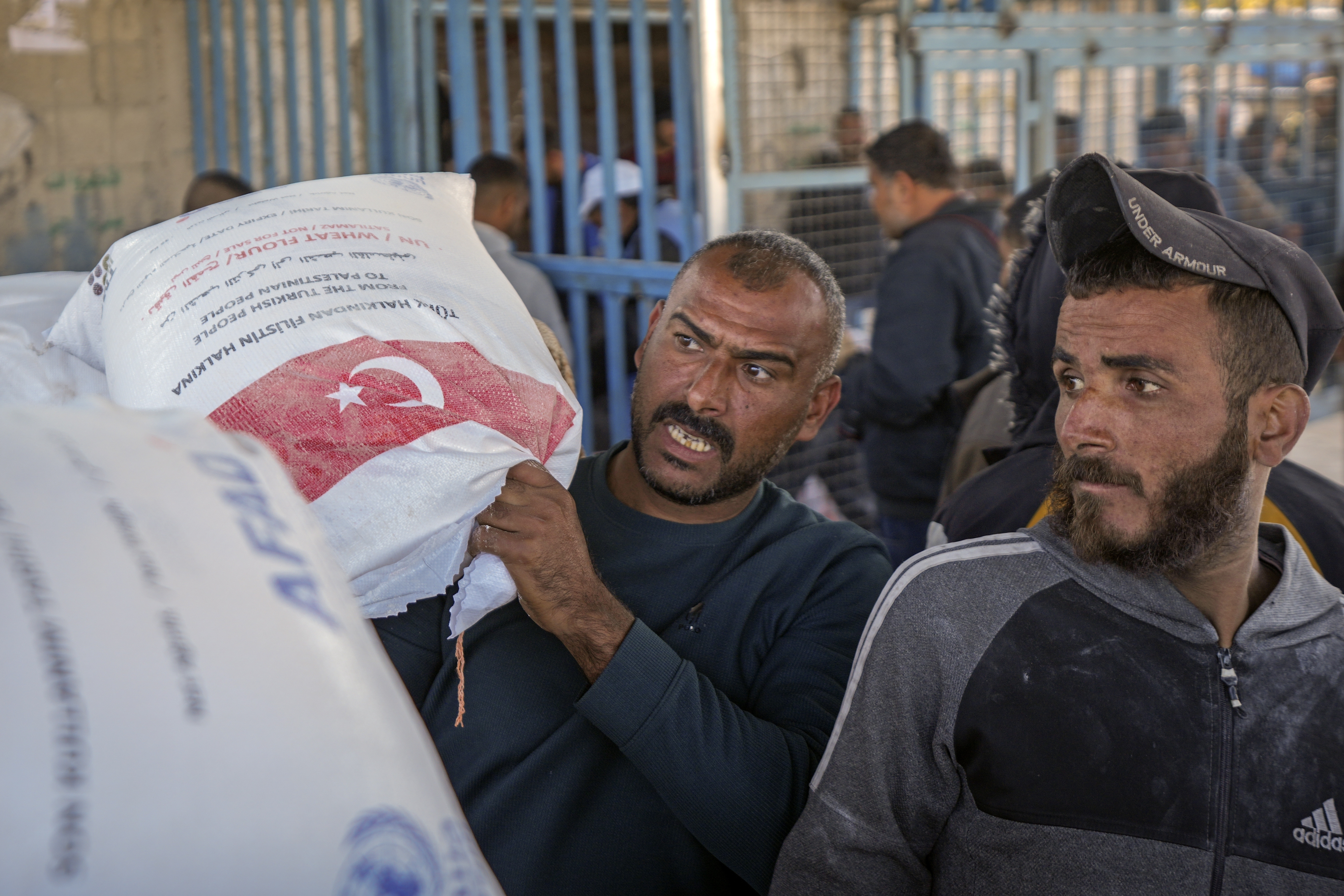 A man grabs a sack of donated flour at a UNRWA distribution center in the Nuseirat refugee camp, Gaza Strip, Tuesday Dec. 3, 2024.(AP Photo/Abdel Kareem Hana)