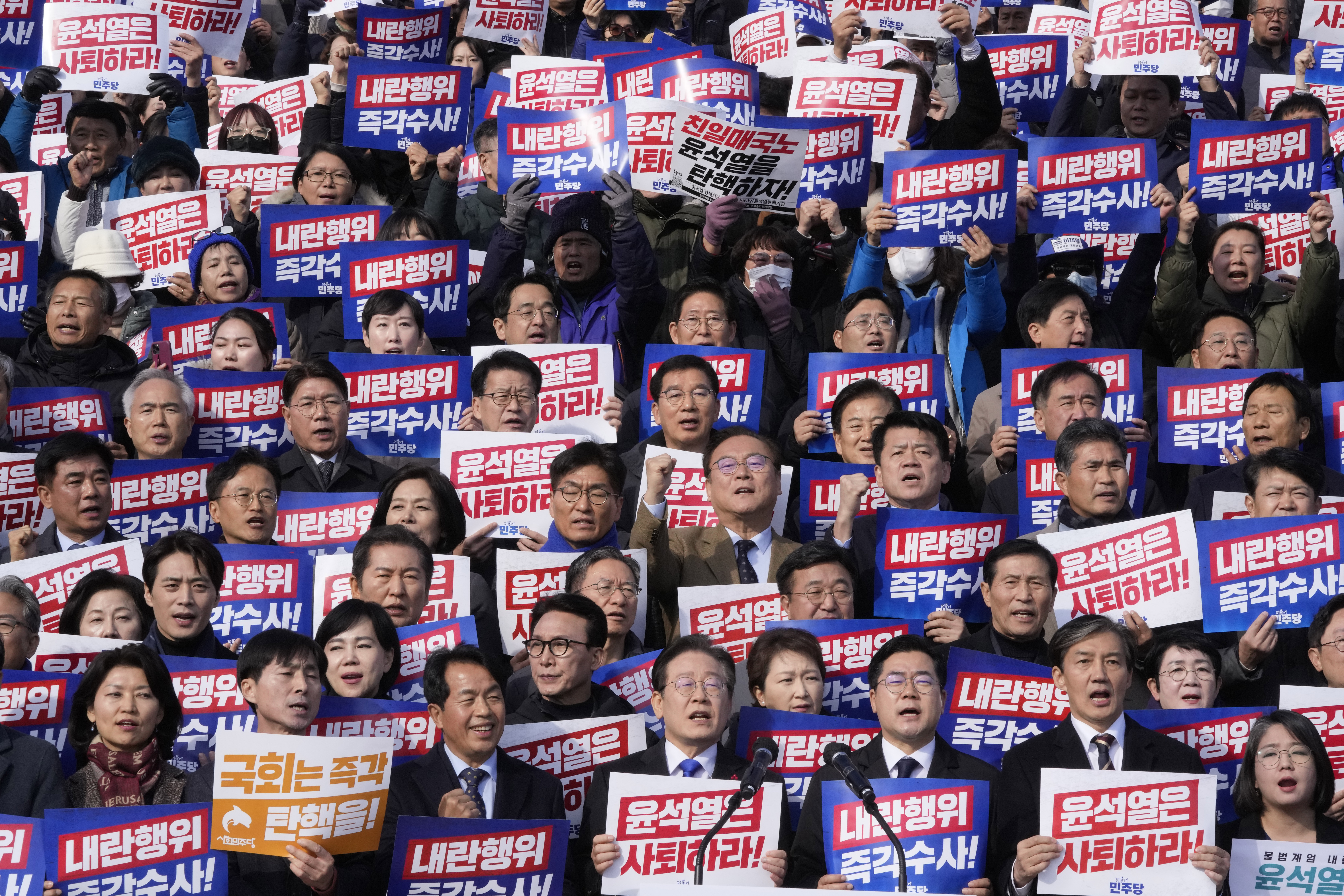 South Korea's main opposition Democratic Party leader Lee Jae-myung, bottom center, shout slogans during a rally against President Yoon Suk Yeol at the National Assembly in Seoul, South Korea, Wednesday, Dec. 4, 2024. The signs read "Yoon Suk Yeol should resign." (AP Photo/Ahn Young-joon)