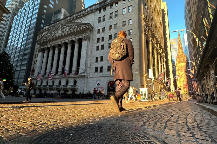 A person walks on Wall St. near the New York Stock Exchange in New York's Financial District on Wednesday, Dec. 4, 2024. (AP Photo/Peter Morgan)