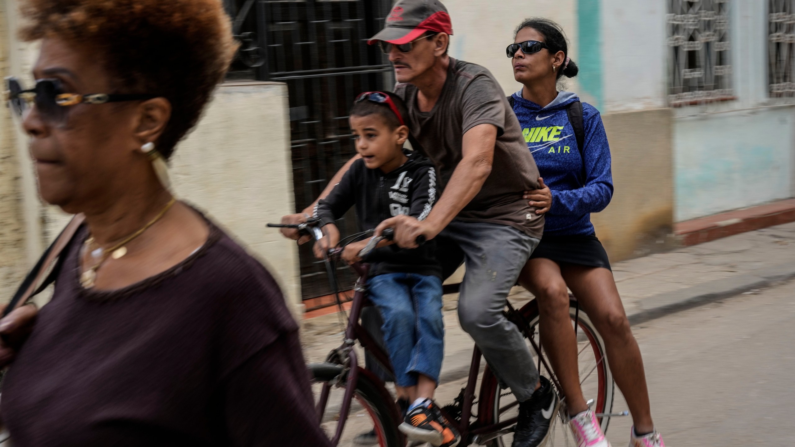 A trio rides a bicycle during a blackout in Havana, Cuba, Wednesday, Dec. 4, 2024. (AP Photo/Ramon Espinosa)