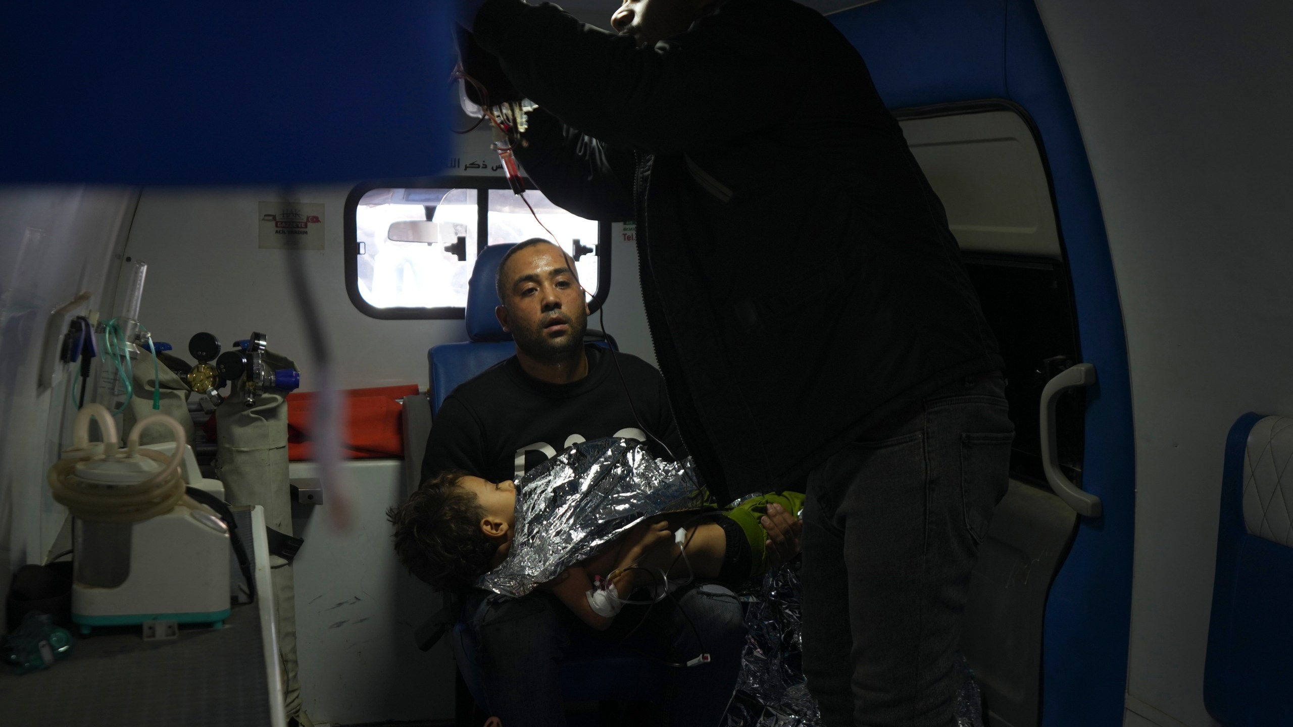 A Palestinian man sits in an ambulance holding a wounded child, following an Israeli bombardment in Nuseirat, central Gaza, after arriving at the Al-Aqsa Martyrs hospital in Deir al-Balah, Gaza Strip Wednesday, Dec. 4, 2024. (AP Photo/Abdel Kareem Hana)