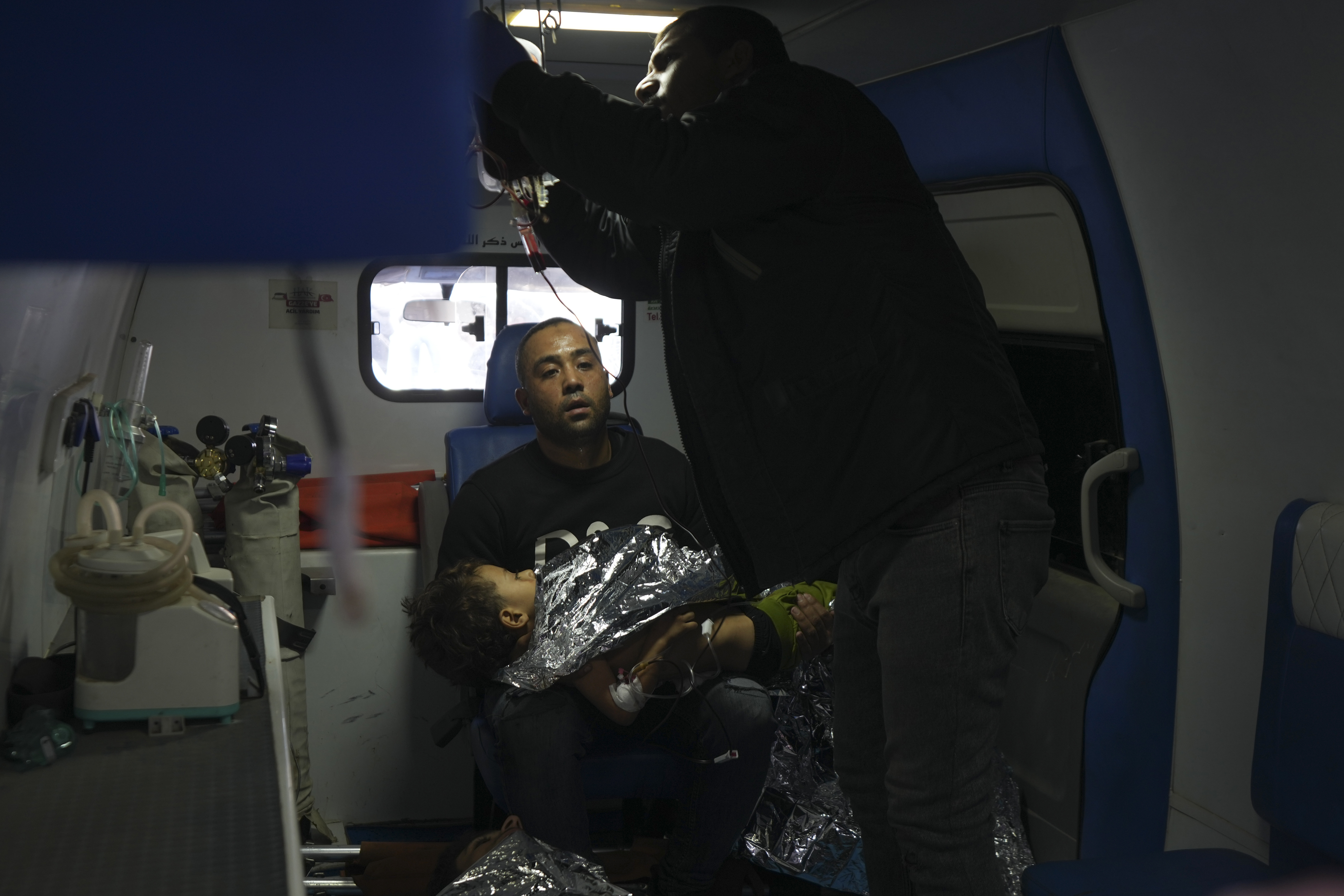 A Palestinian man sits in an ambulance holding a wounded child, following an Israeli bombardment in Nuseirat, central Gaza, after arriving at the Al-Aqsa Martyrs hospital in Deir al-Balah, Gaza Strip Wednesday, Dec. 4, 2024. (AP Photo/Abdel Kareem Hana)