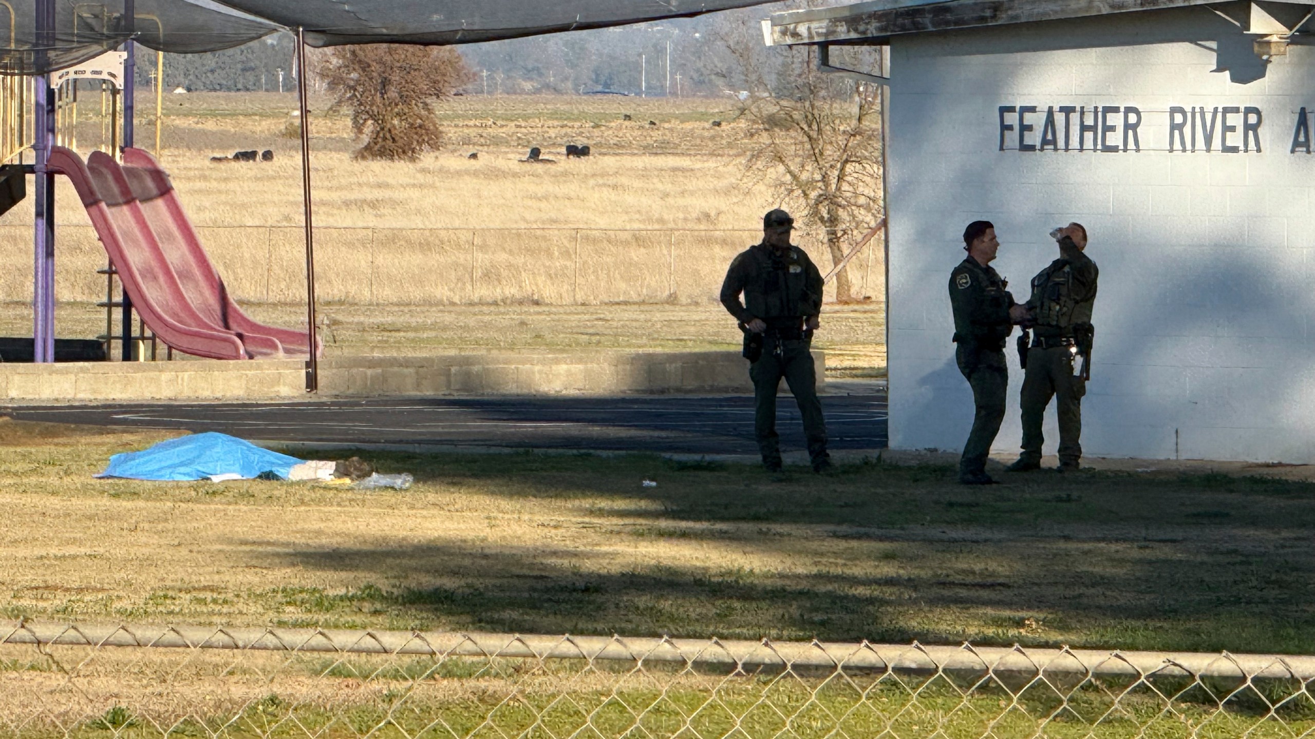 Police officers stand near a body covered by a tarp outside of Feather River Adventist School after a shooting Wednesday, Dec. 4, 2024, in Oroville, Calif. (Michael Weber/The Chico Enterprise-Record via AP)