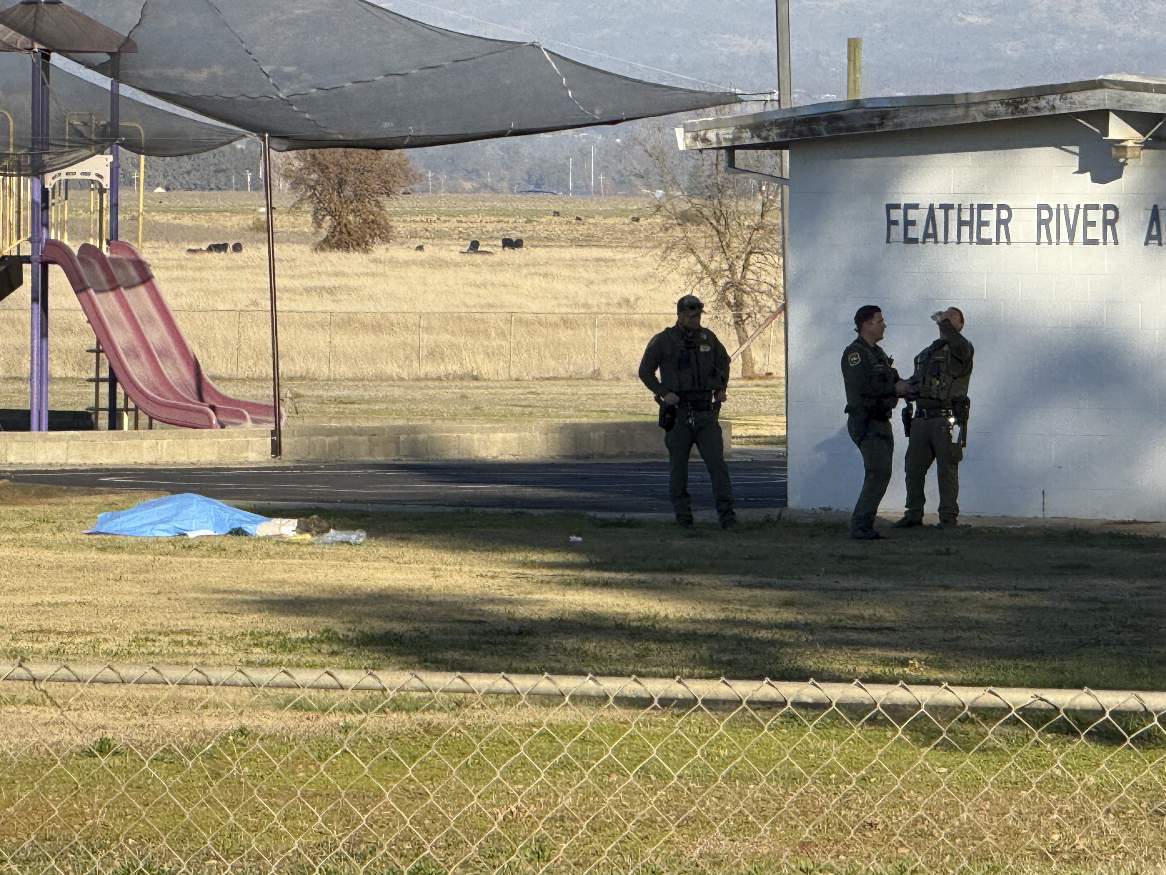 Police officers stand near a body covered by a tarp outside of Feather River Adventist School after a shooting Wednesday, Dec. 4, 2024, in Oroville, Calif. (Michael Weber/The Chico Enterprise-Record via AP)