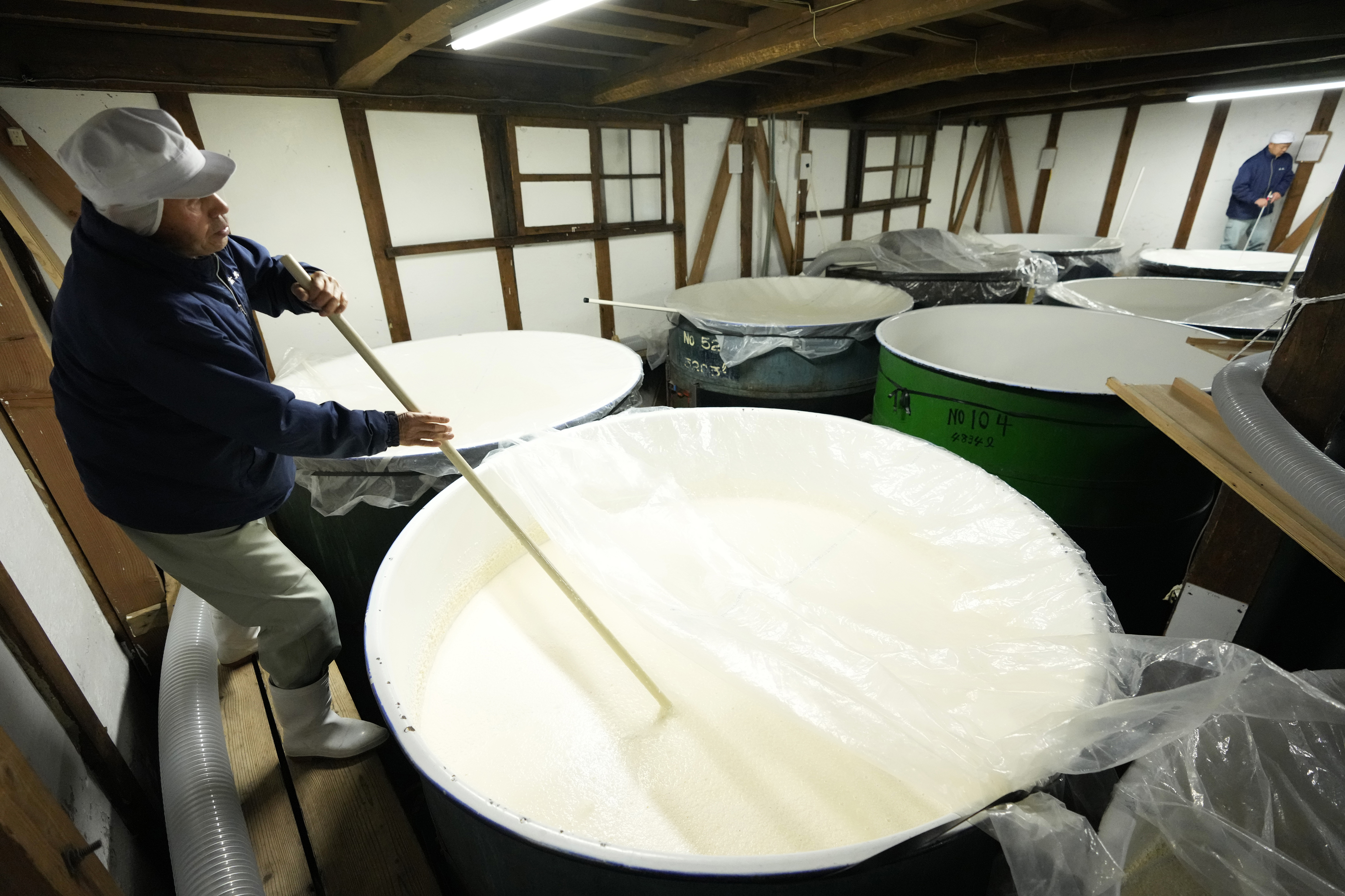 Seasonal employee Shigeru Kikuchi stirs "moromi," or fermentation mash, following the mixture of sake ingredients including steamed rice with koji mold and yeast, in a sake making process at the Koten sake brewery in Okaya, Nagano prefecture, central Japan, Saturday, Nov. 30, 2024. (AP Photo/Hiro Komae)