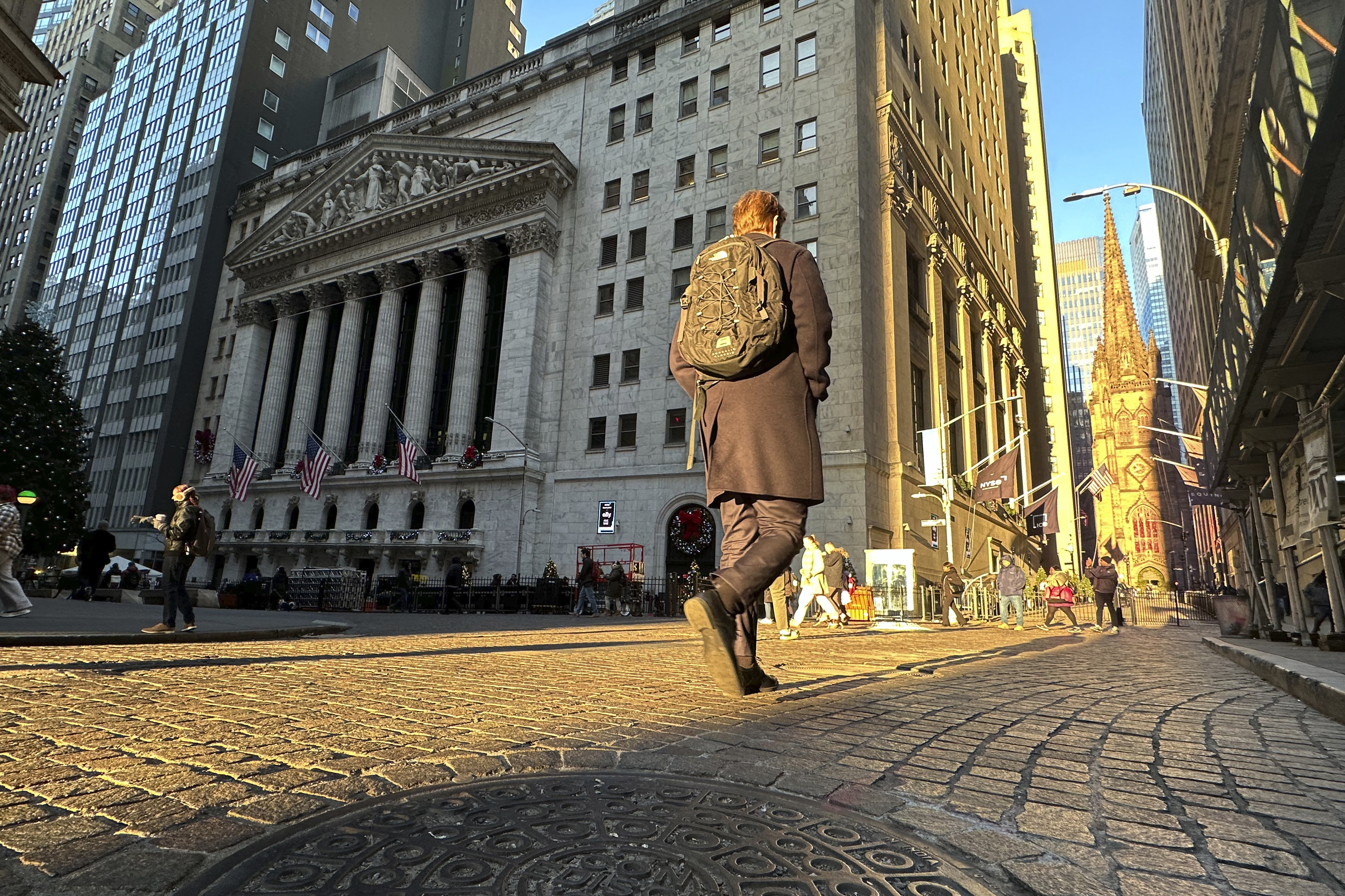 A person walks on Wall St. near the New York Stock Exchange in New York's Financial District on Wednesday, Dec. 4, 2024. (AP Photo/Peter Morgan)