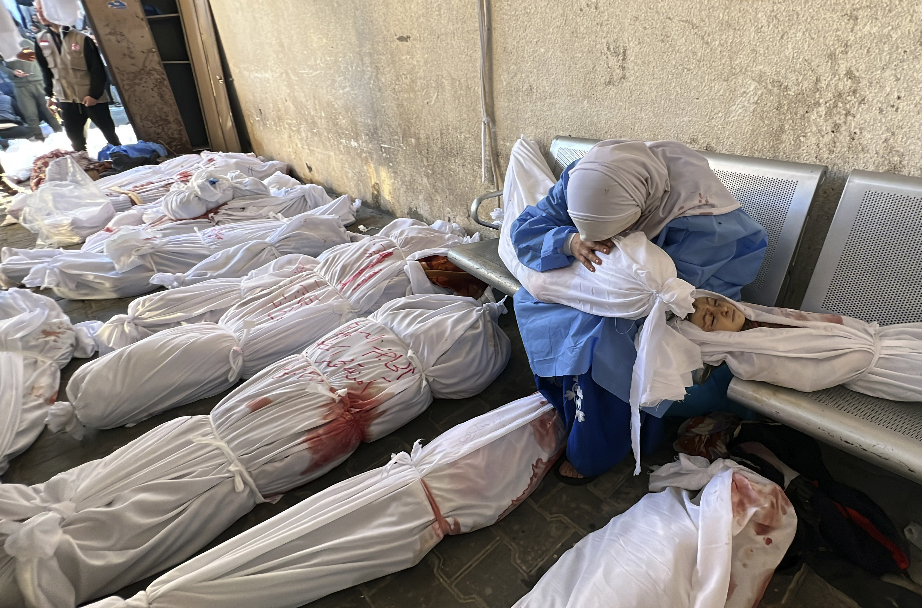 FILE - A Palestinian woman reacts over the body of a child as she sits by bodies of Palestinians killed by Israeli airstrikes on Jabaliya refugee camp, at the Indonesian hospital, northern Gaza Strip, Nov. 18, 2023. (AP Photo/Ahmed Alarini, File)