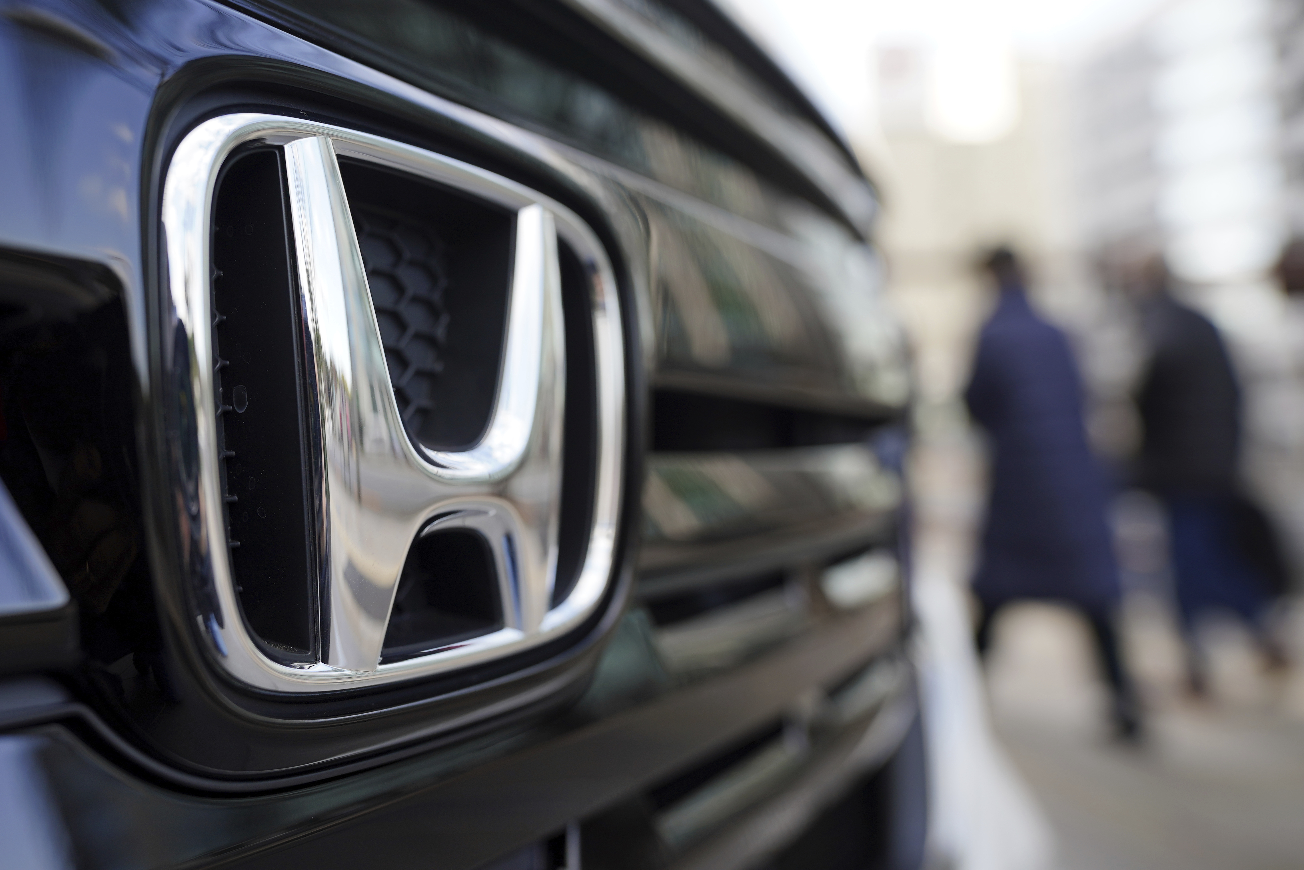 FILE - People walk near the logo of Honda Motor Company at a showroom on Feb. 8, 2022, in Tokyo. (AP Photo/Eugene Hoshiko, File)