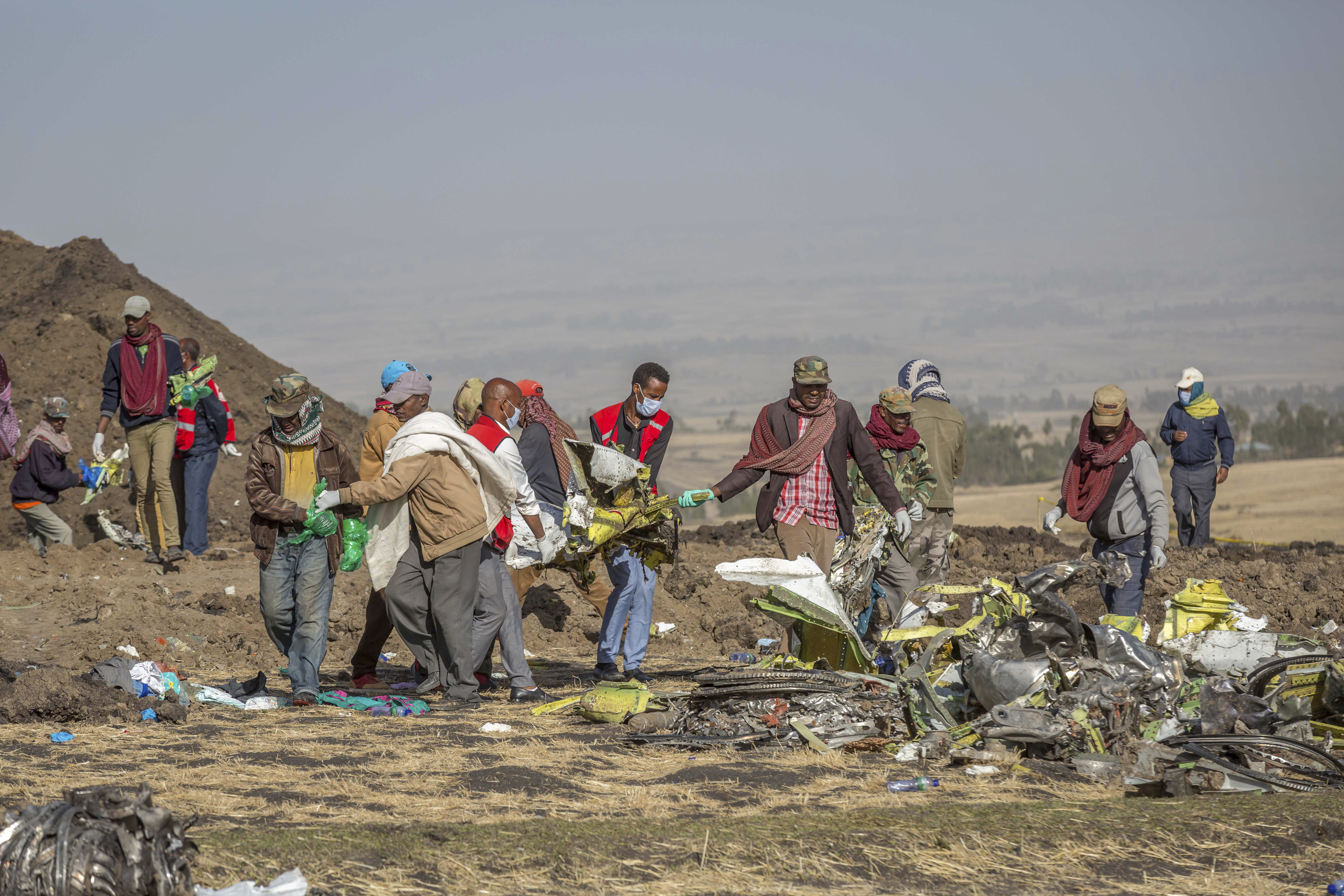 FILE - Debris is carried at the scene of an Ethiopian Airlines flight crash near Bishoftu, or Debre Zeit, south of Addis Ababa, Ethiopia, on March 11, 2019. A spokesman says Ethiopian Airlines has grounded all its Boeing 737 Max 8 aircraft as a safety precaution, following the crash of one of its planes in which 157 people were killed. (AP Photo/Mulugeta Ayene)