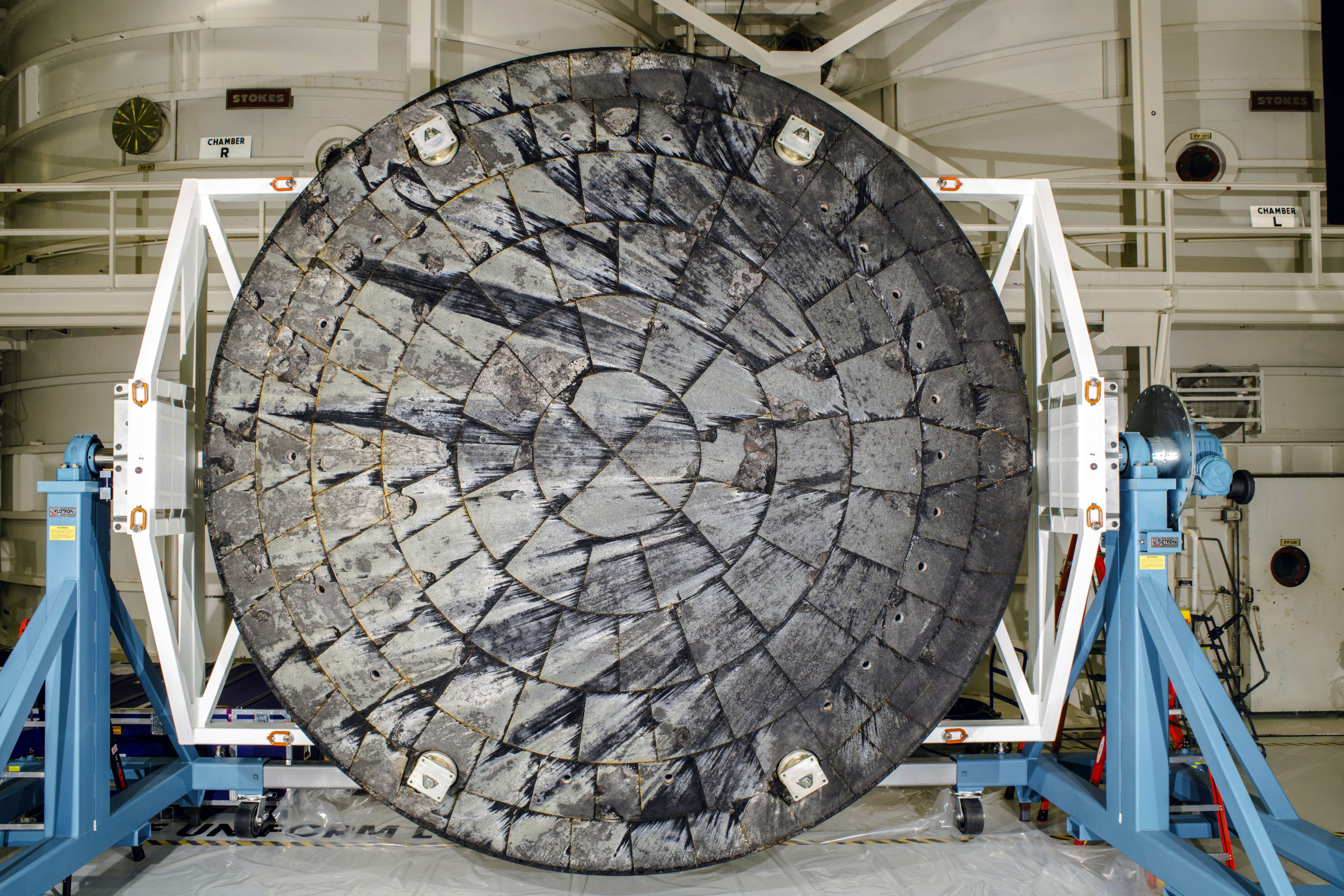 This Feb. 3, 2024 image provided by NASA shows the Orion spacecraft heat shield following the Artemis I test flight after it was was removed from the crew module inside the Operations and Checkout Building and rotated for inspection at the Kennedy Space Center in Cap Canaveral, Fla. (NASA via AP)