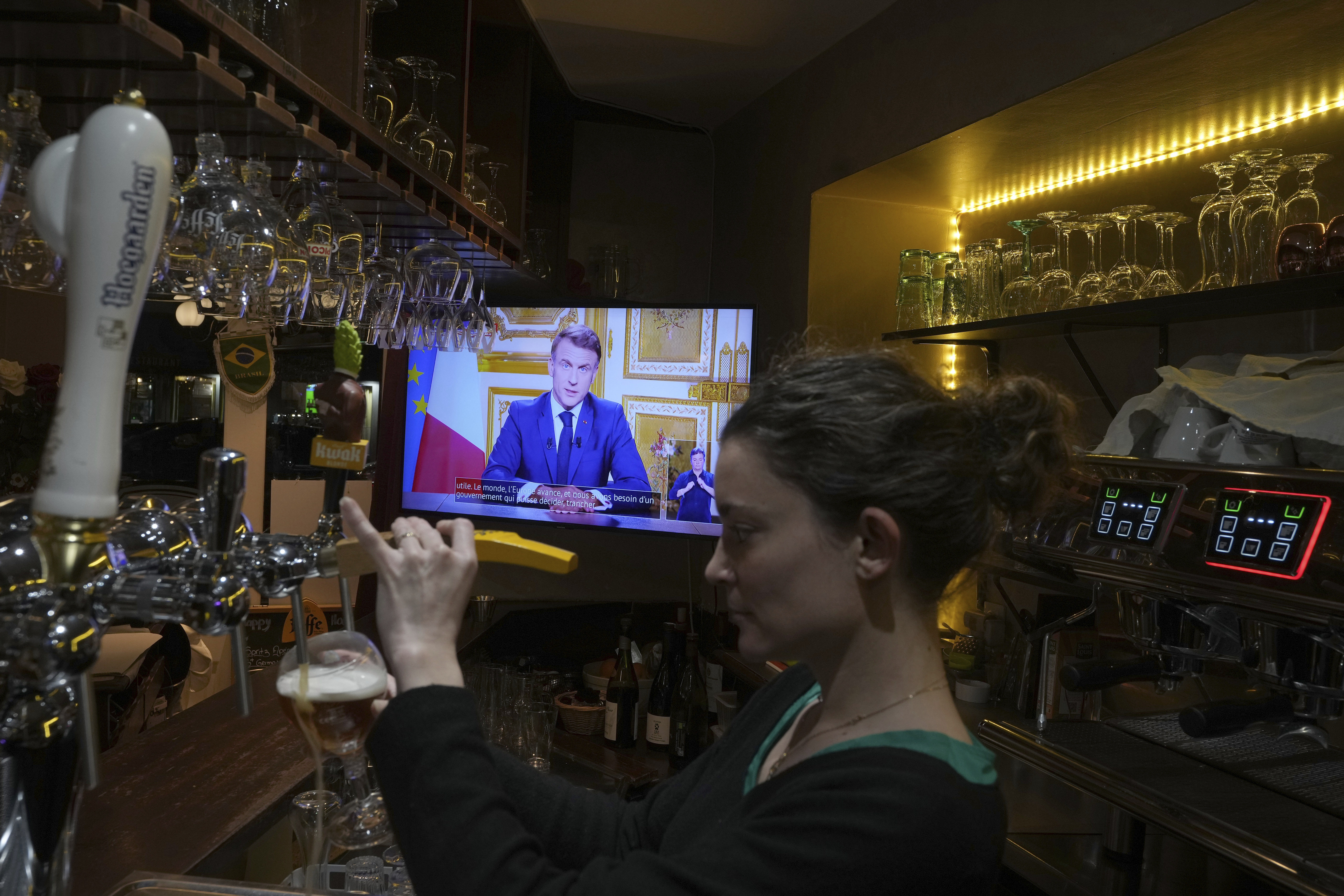 A waiter serves a beer as French President Emmanuel Macron addresses the nation following the resignation of ousted Prime Minister Michel Barnier, a day after a historic no-confidence vote at the National Assembly left France without a functioning government. Thursday, Dec. 5, 2024 in Versailles, outside Paris. (AP Photo/Michel Euler)