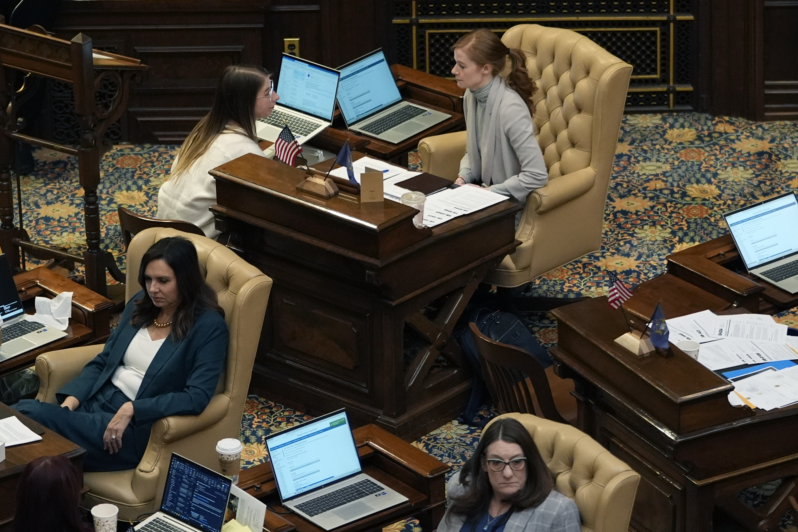 Michigan State Sen. Mallory McMorrow, top, talks with a staffer on the Senate floor, Wednesday, Dec. 4, 2024, in Lansing, Mich. (AP Photo/Carlos Osorio)